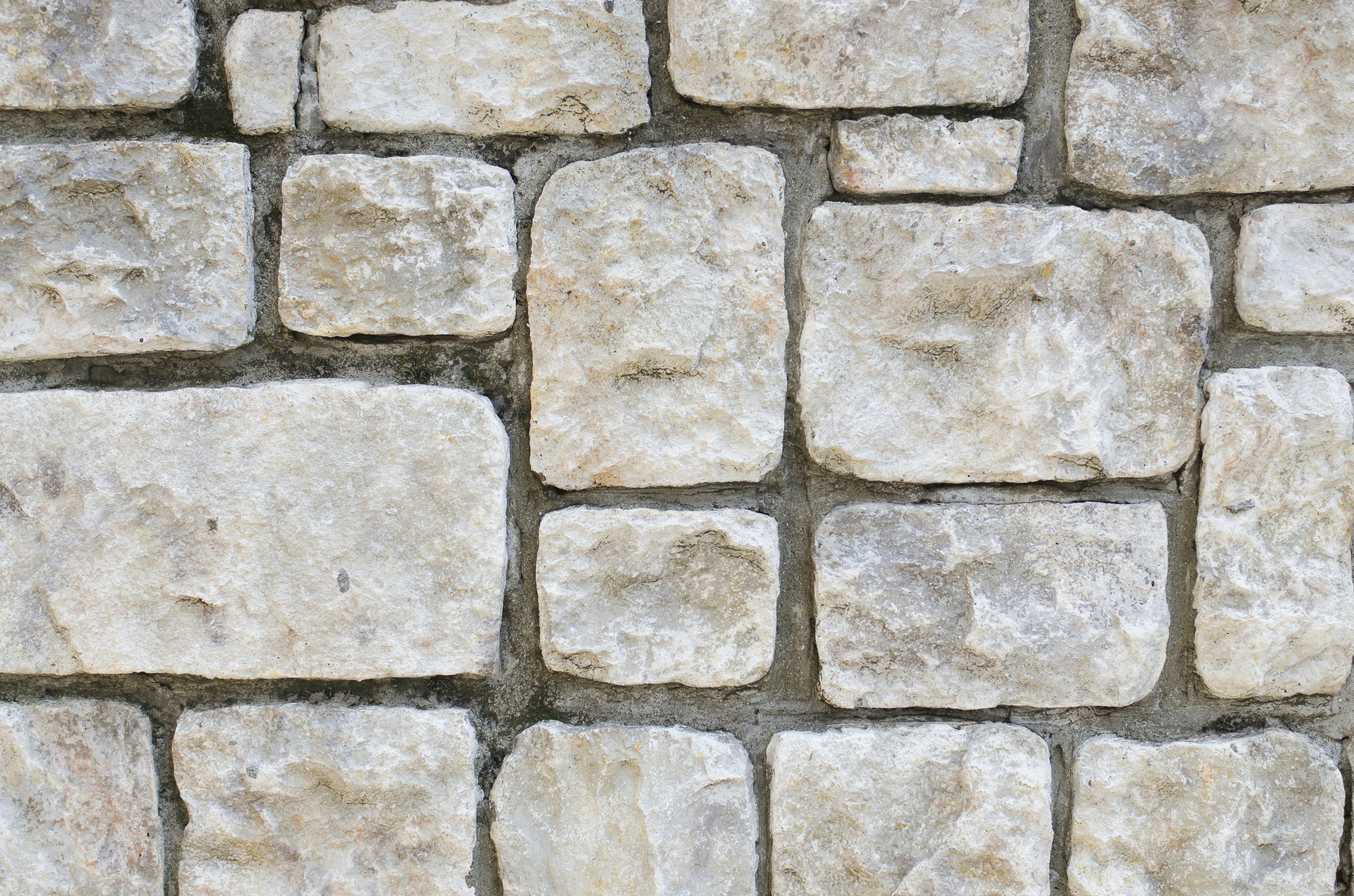 Textur einer weißen Steinmauer mit verschiedenen geformten Steinen angeordnet