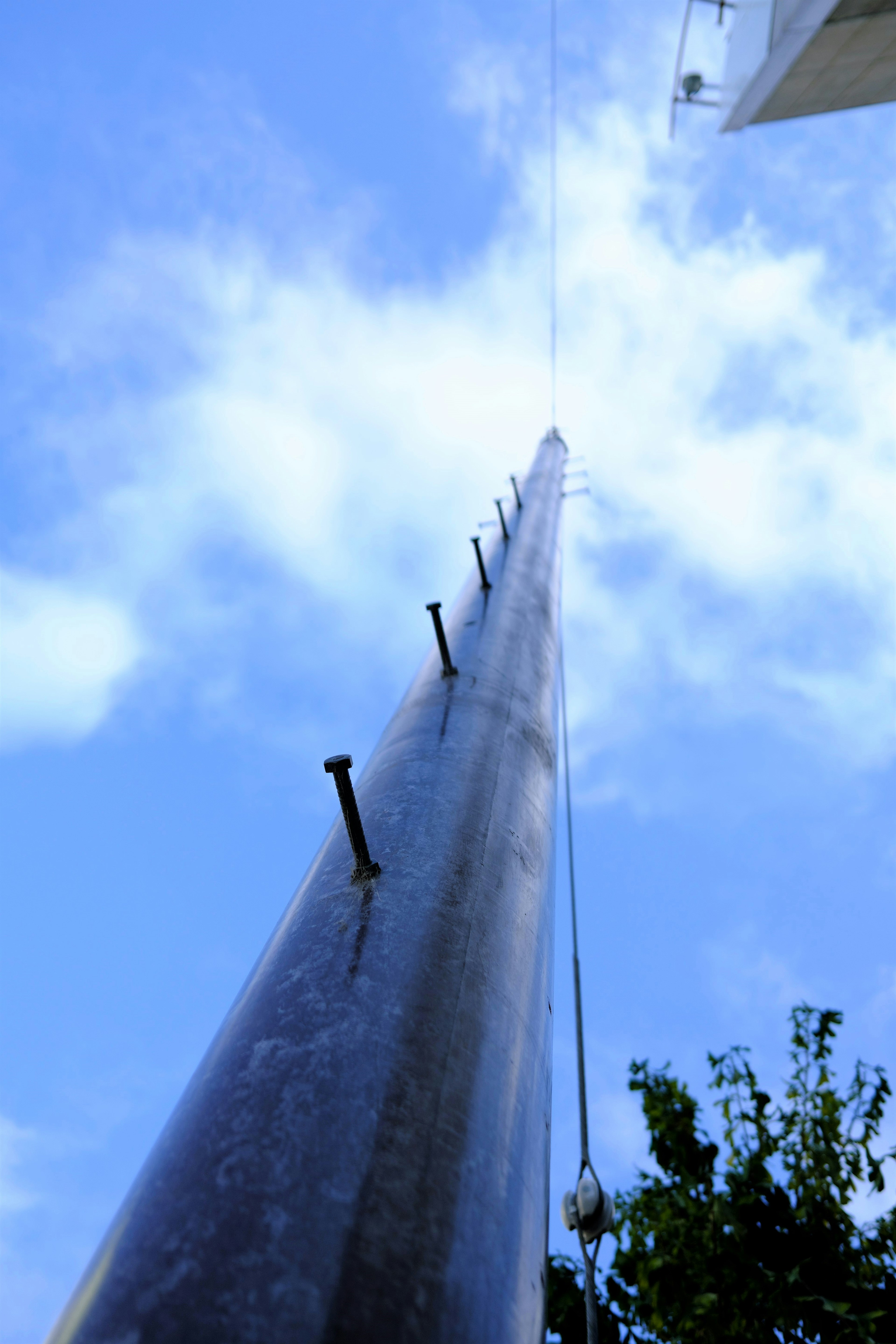 Tall pole reaching towards the sky with blue sky and clouds