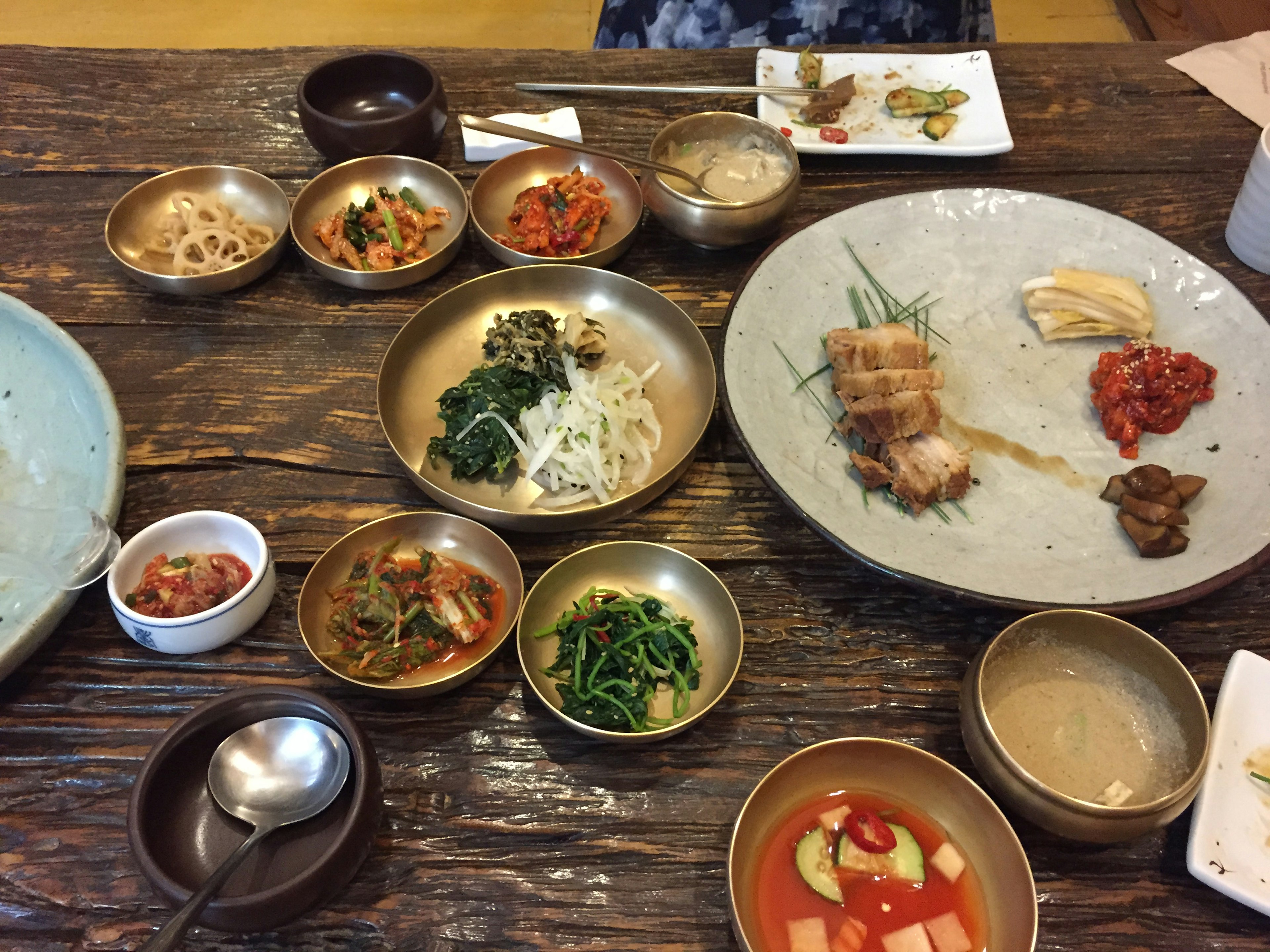 A spread of Korean dishes with various side dishes on a wooden table