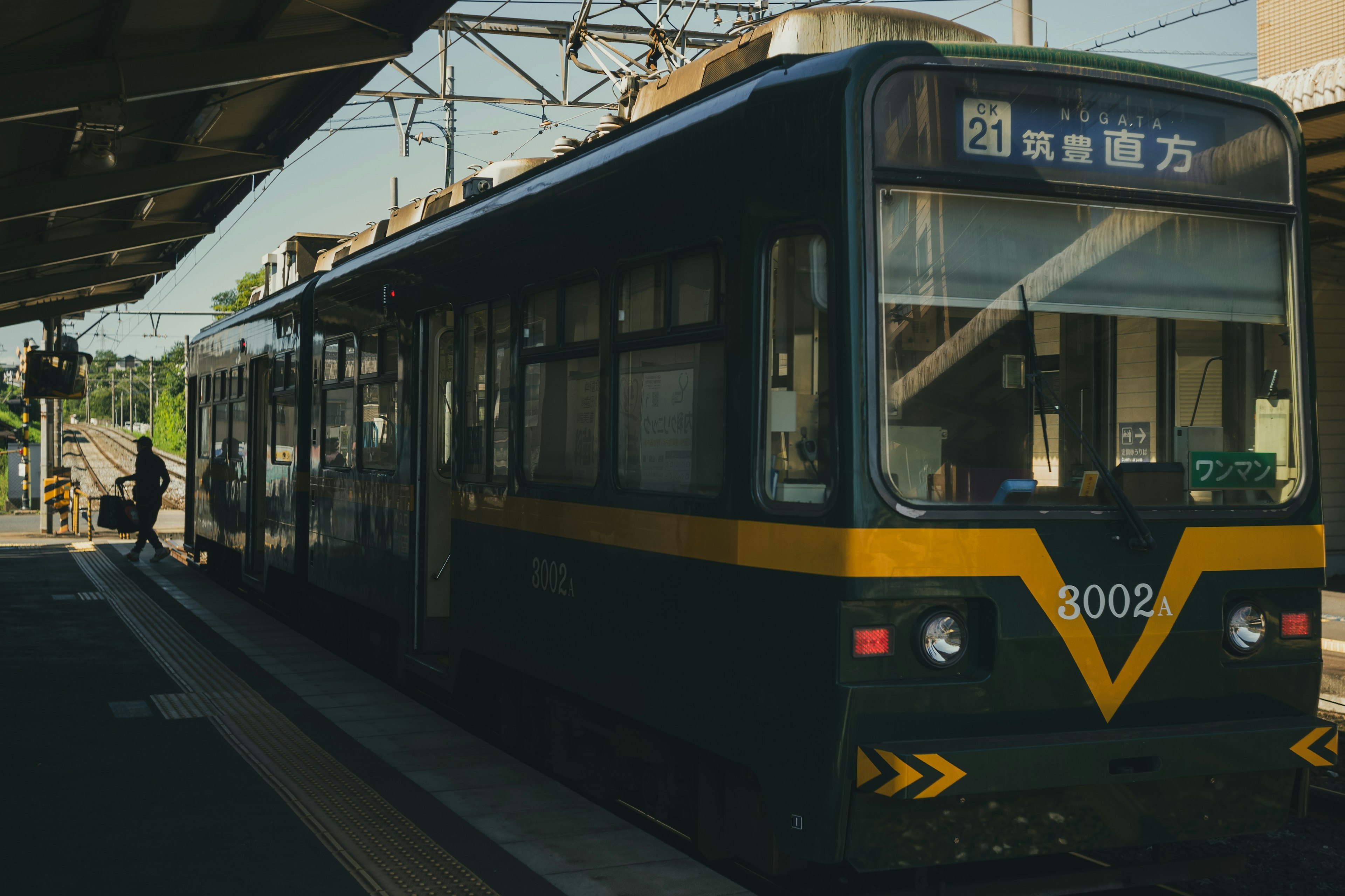 黄色いラインの入った黒い路面電車が駅に停車中