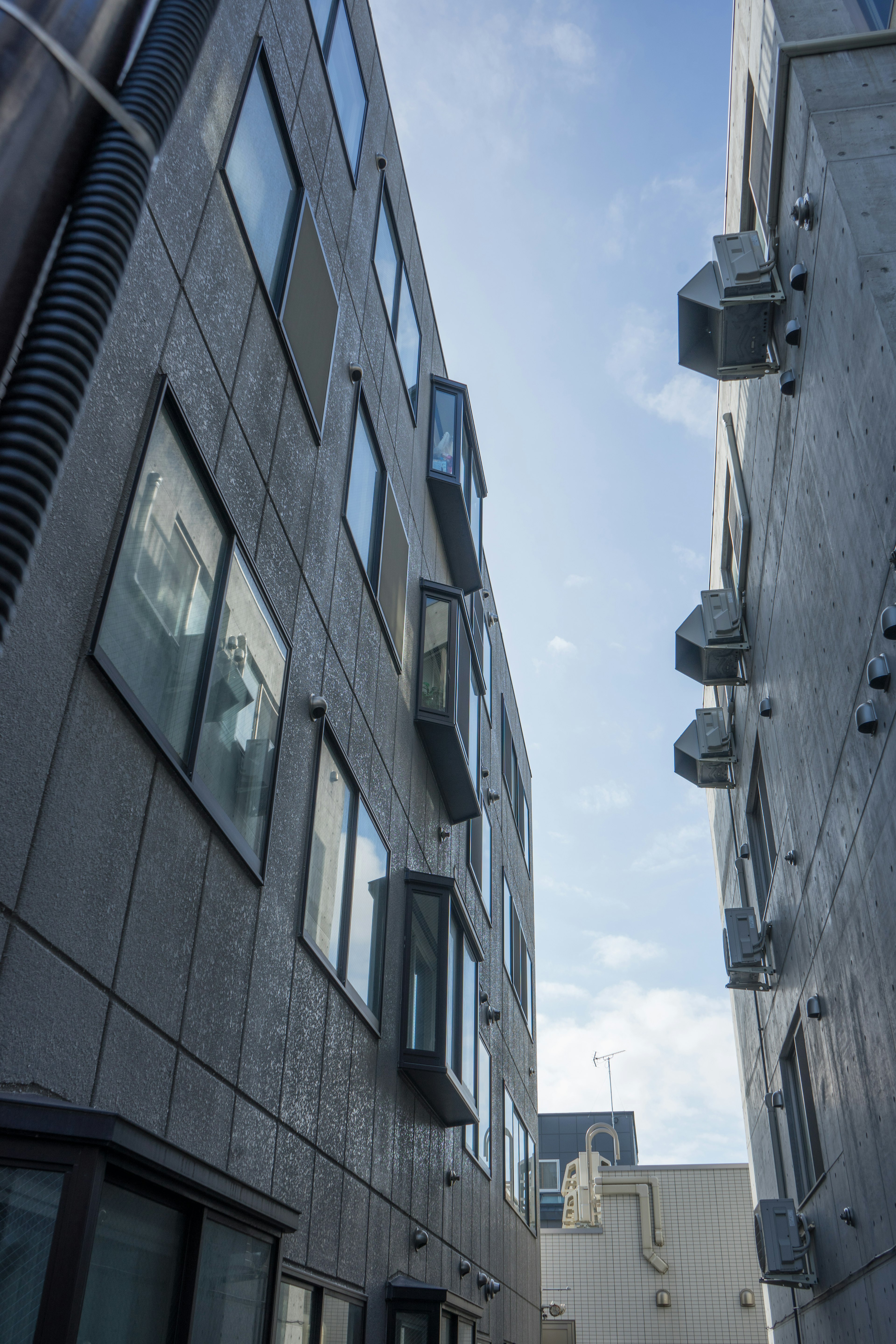 Muros de edificio de concreto con ventanas y vista del cielo entre ellos