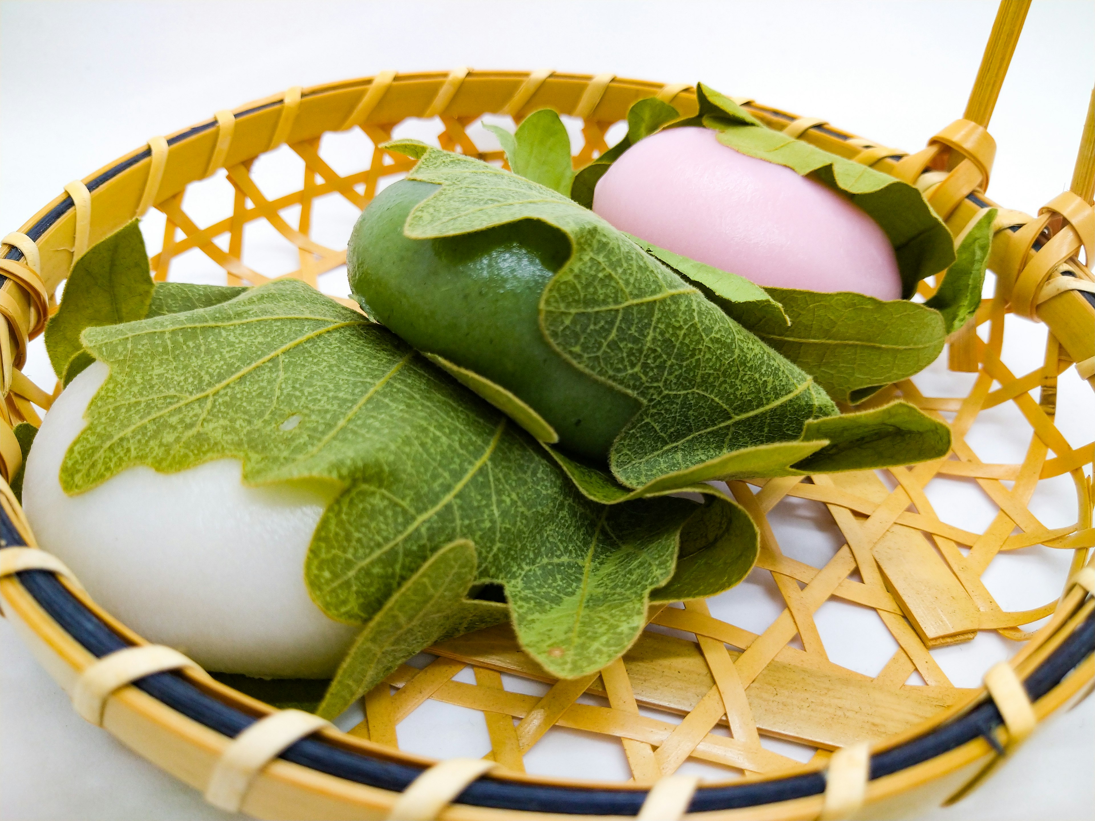 Colorful Japanese sweets wrapped in leaves placed in a bamboo basket