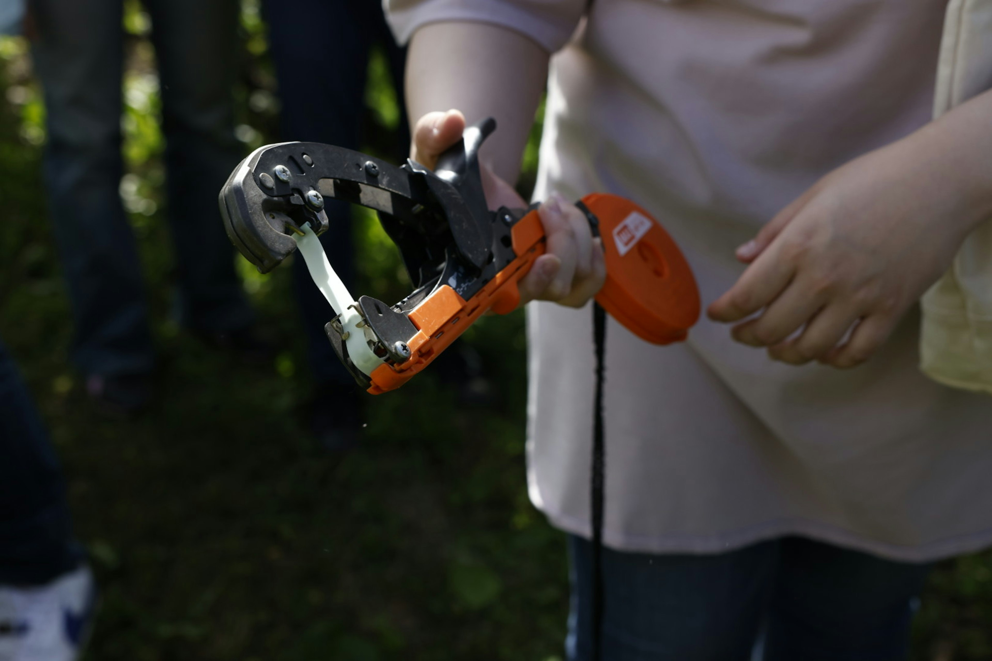 Imagen de una herramienta naranja sostenida en la mano con partes metálicas