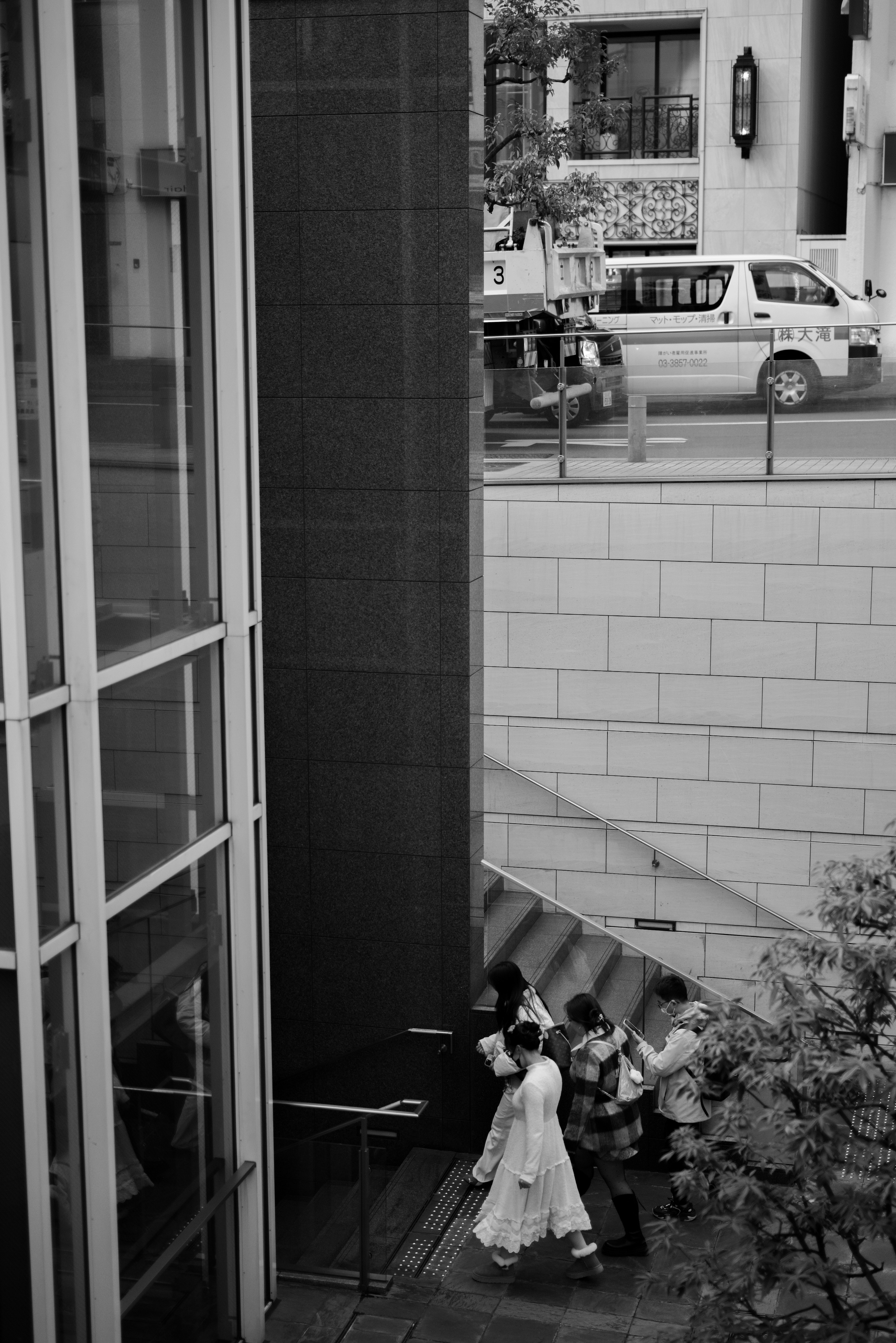 Group of people in white clothing walking up stairs in a black and white urban scene