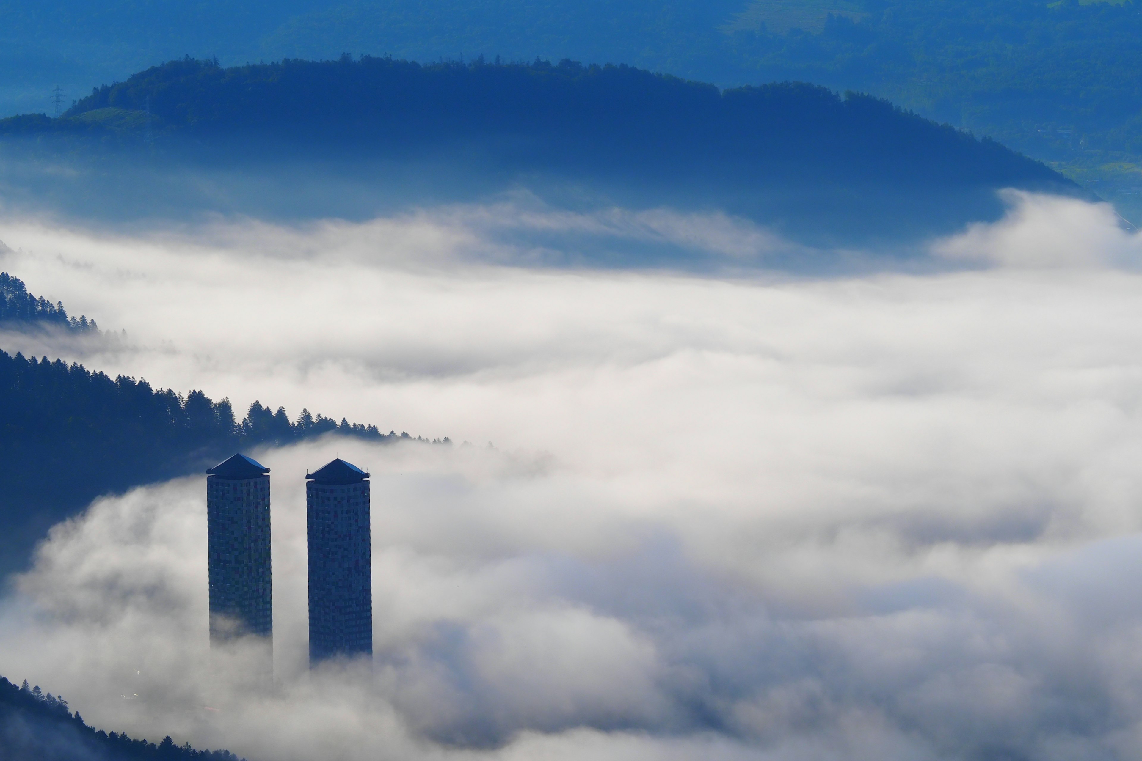 Two towers emerging from foggy mountain landscape