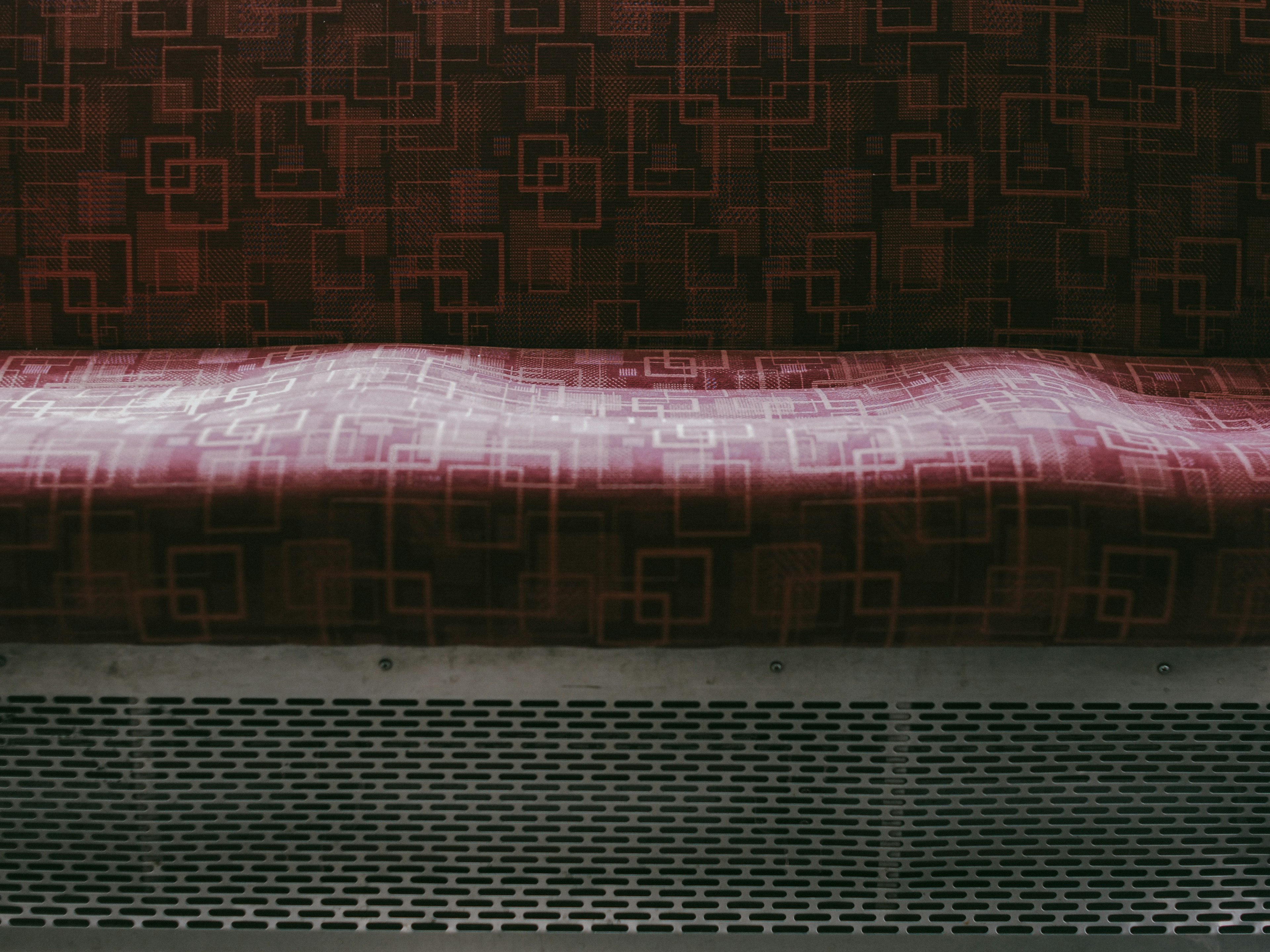 Interior of a vehicle with a red patterned seat and metal vent