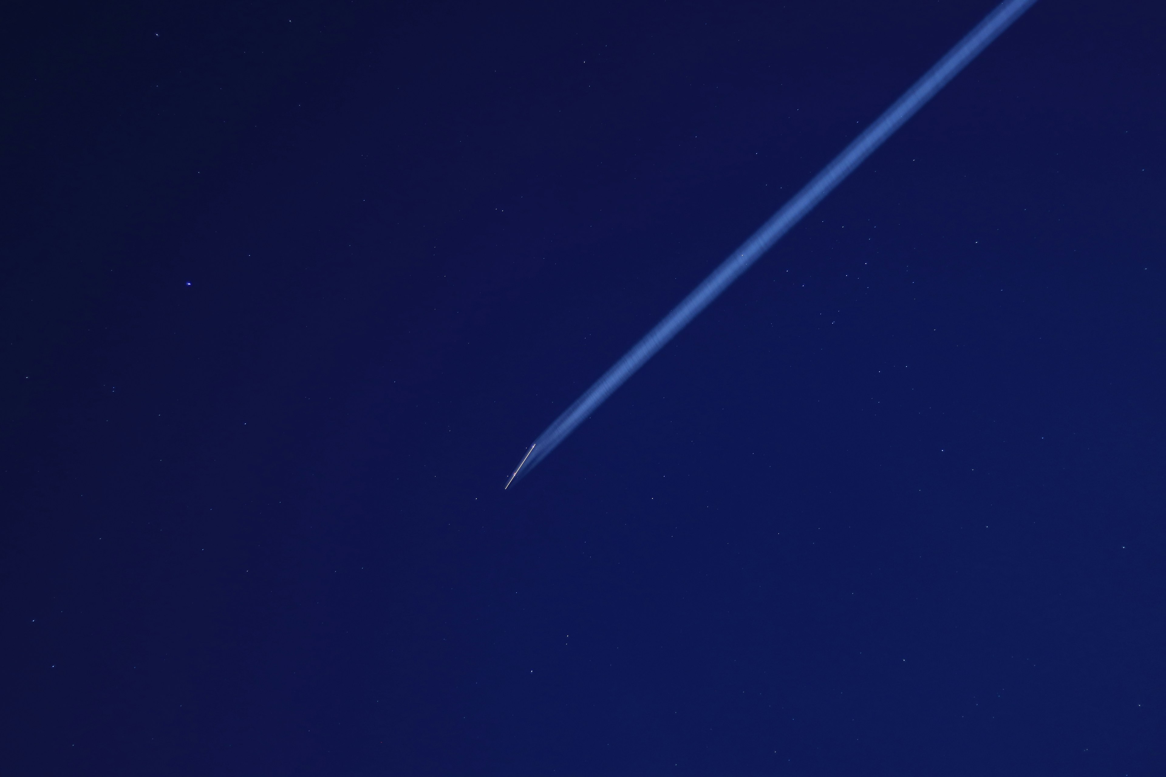 Airplane contrail against a dark blue sky