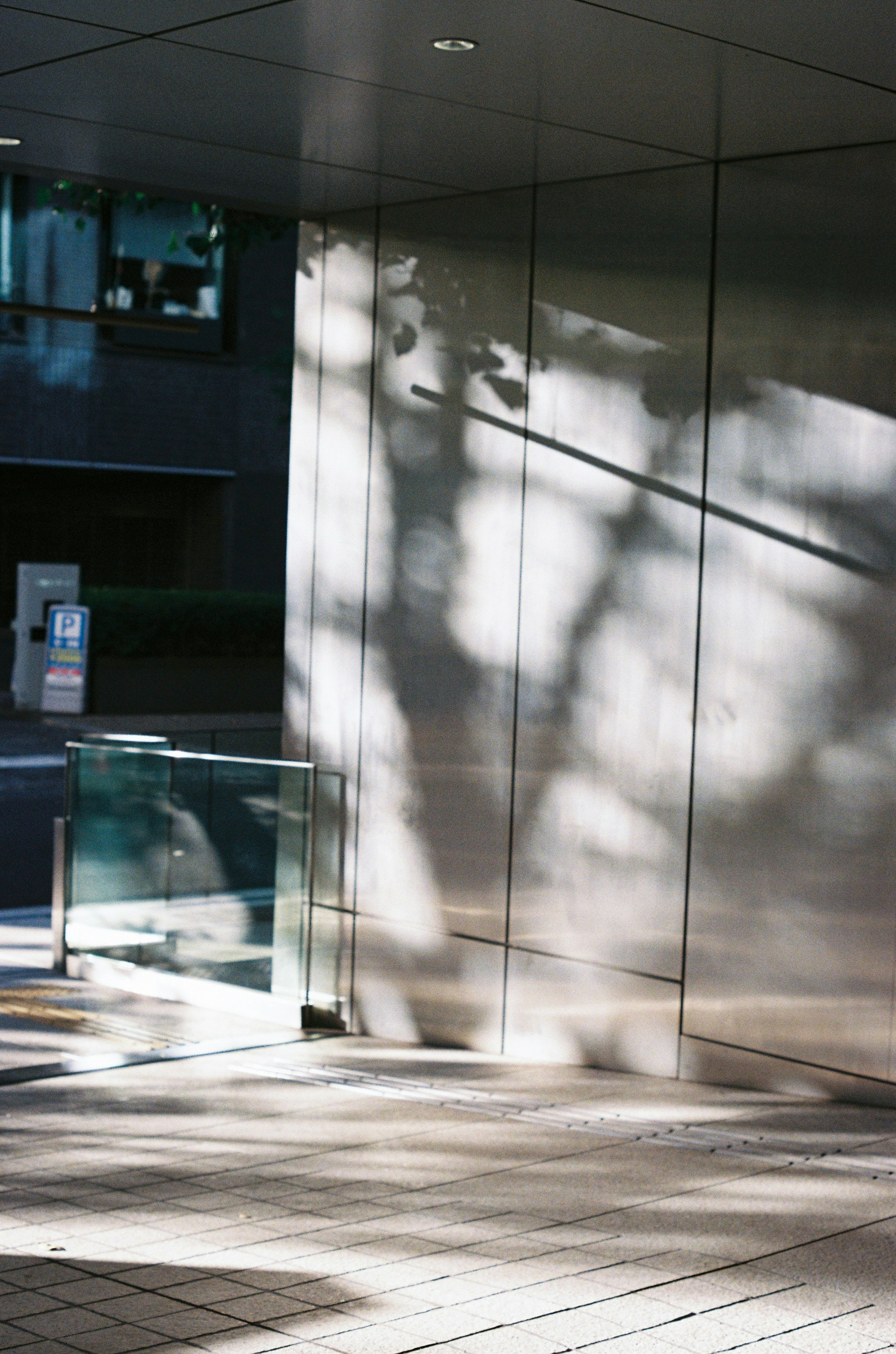 Shadows on the entrance of a modern building with reflective surfaces