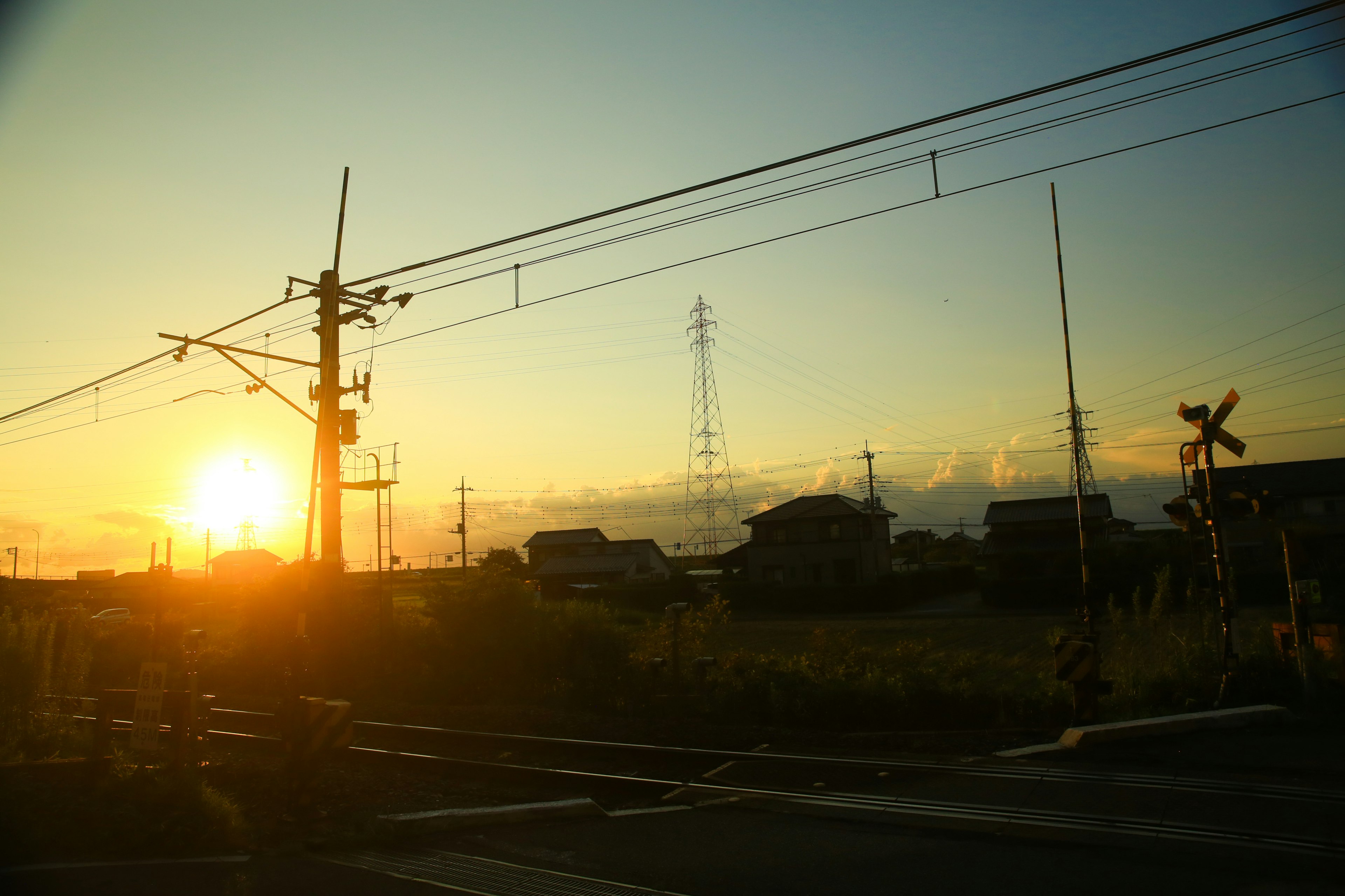 Tramonto su binari ferroviari con pali elettrici sullo sfondo