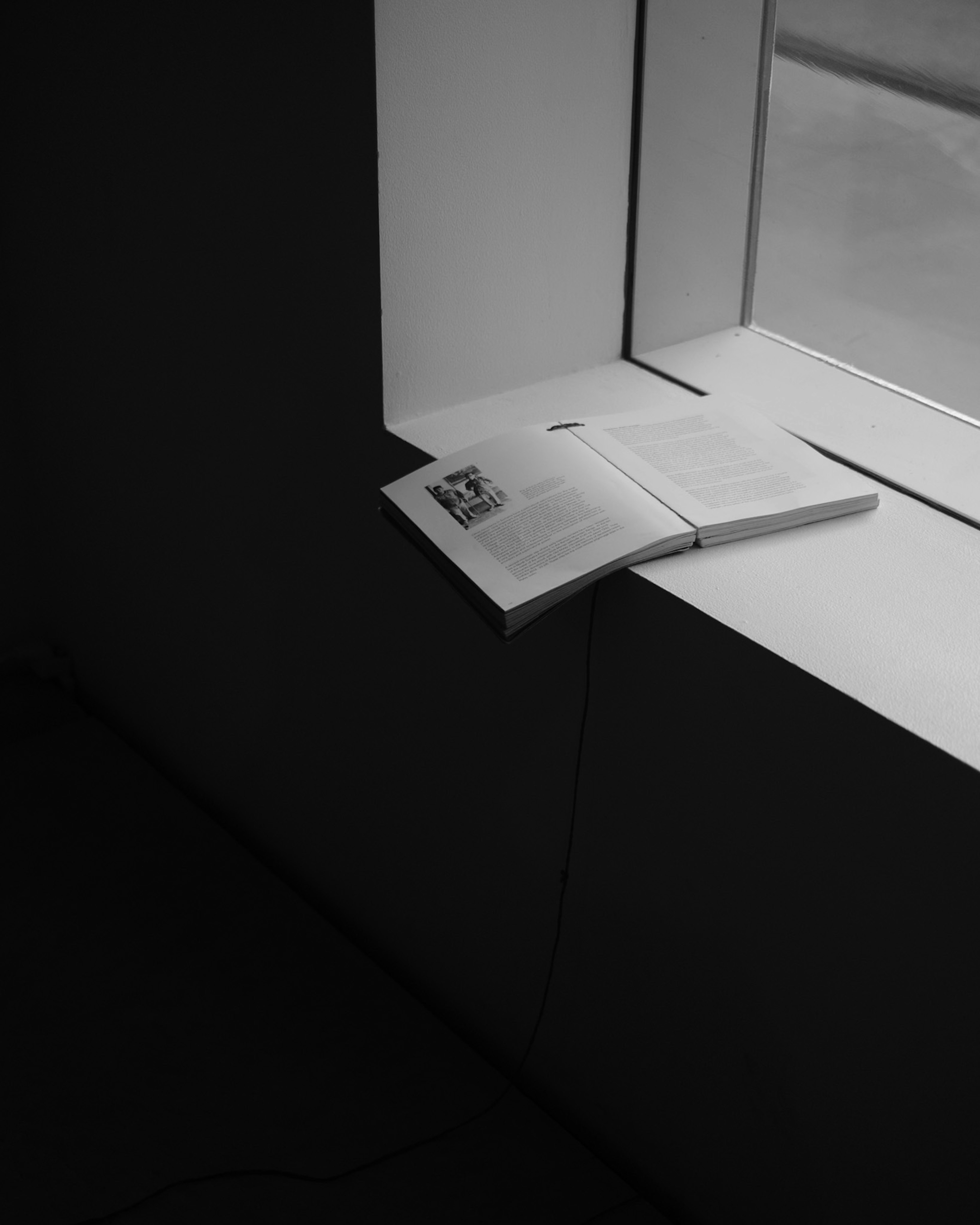 Black and white photo of a book resting on a windowsill