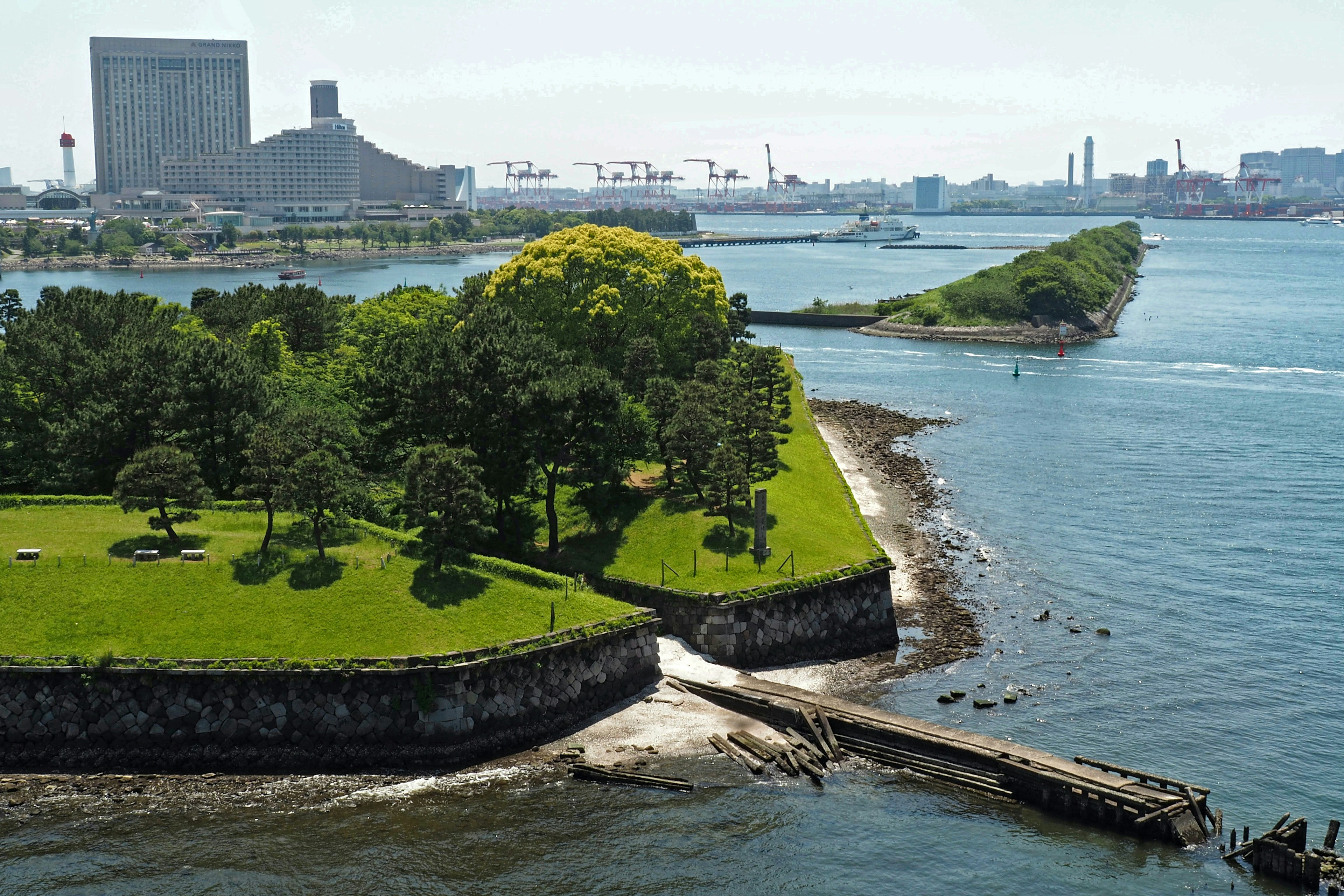 Lush green park with waterfront view buildings and port in the background