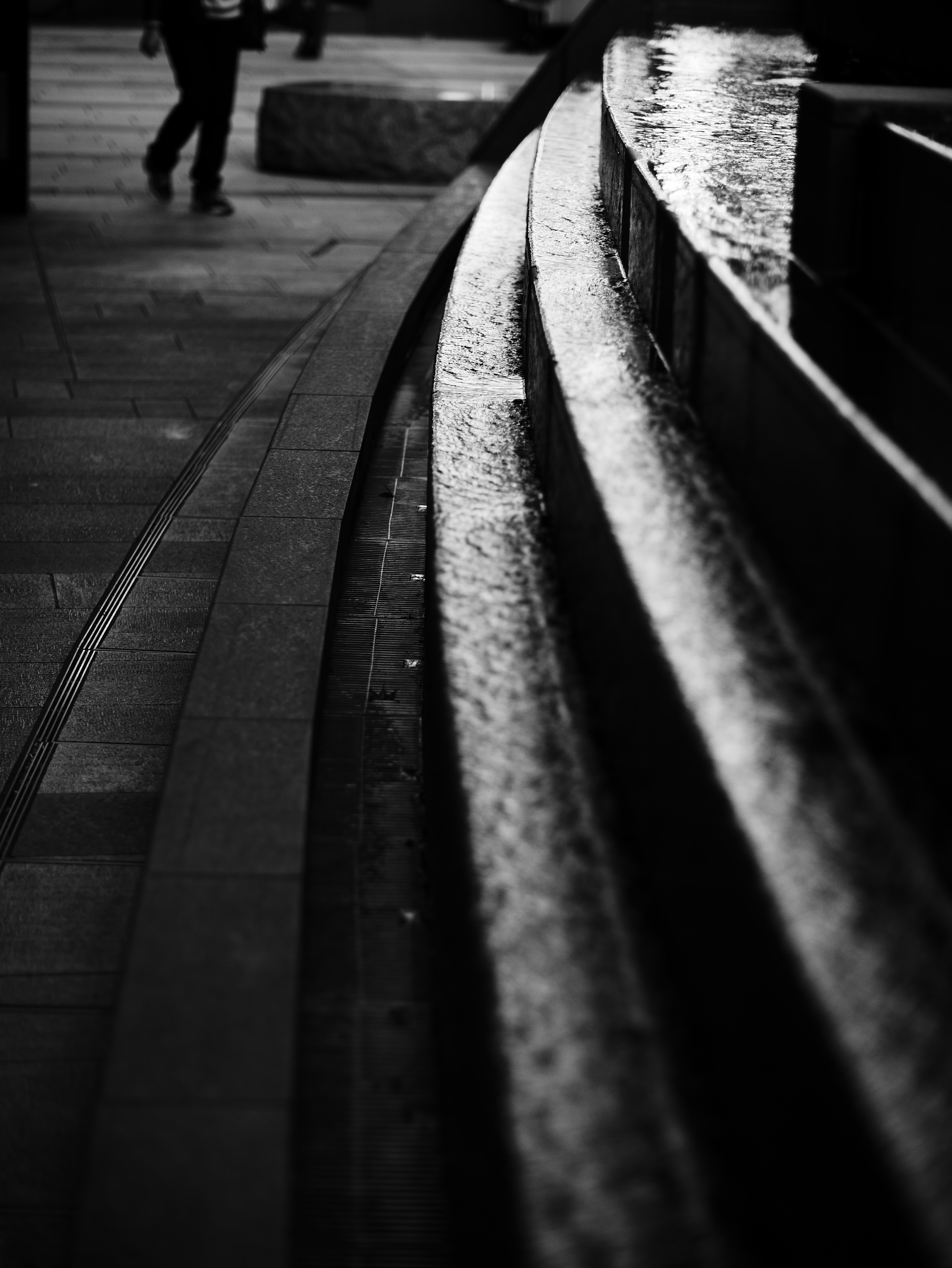 Black and white image of flowing water along curved stone steps