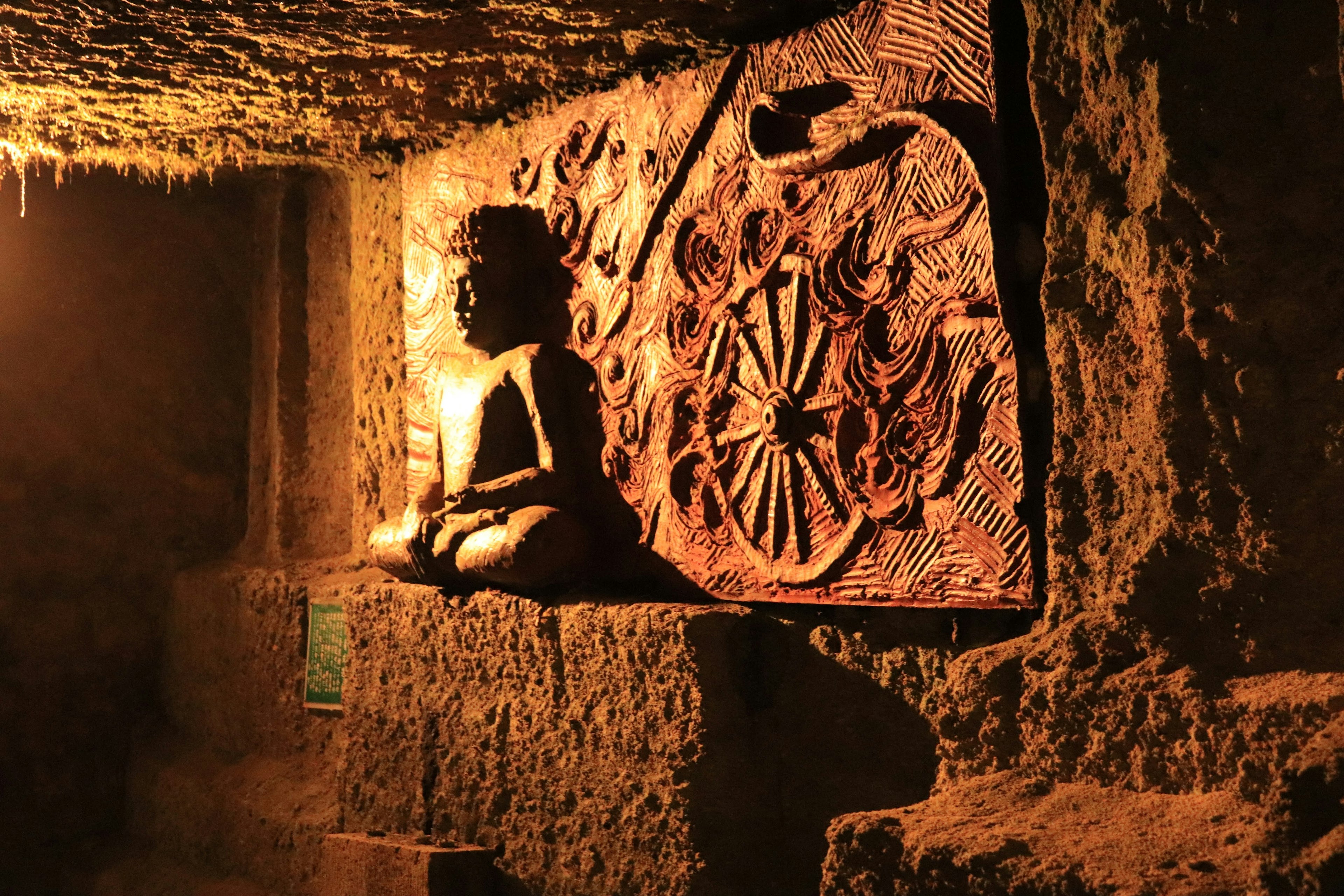 Scène avec une statue de Bouddha et une fresque dans une grotte