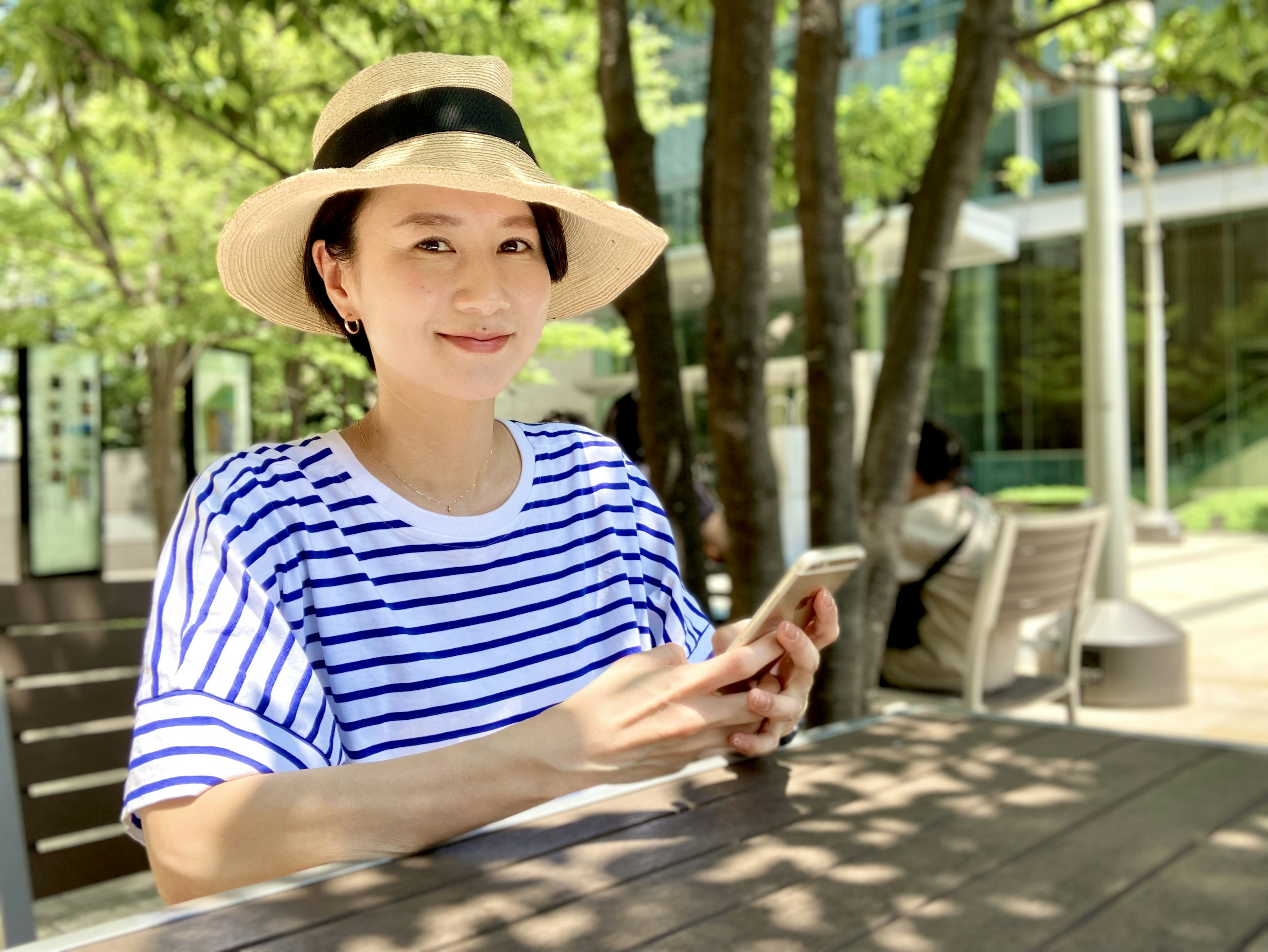 Woman in a striped shirt wearing a hat sitting outdoors