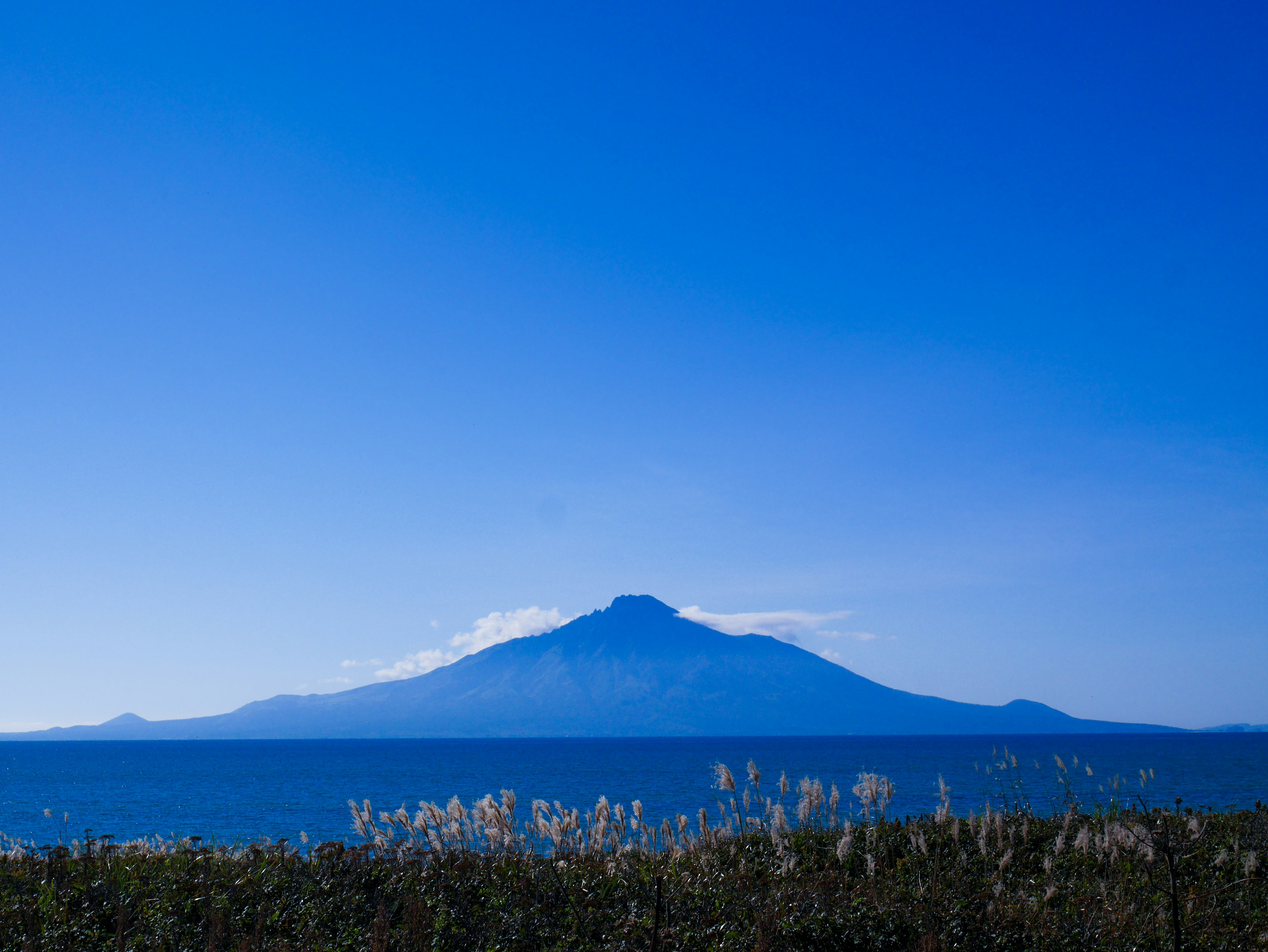 青空の下に広がる海と山の風景