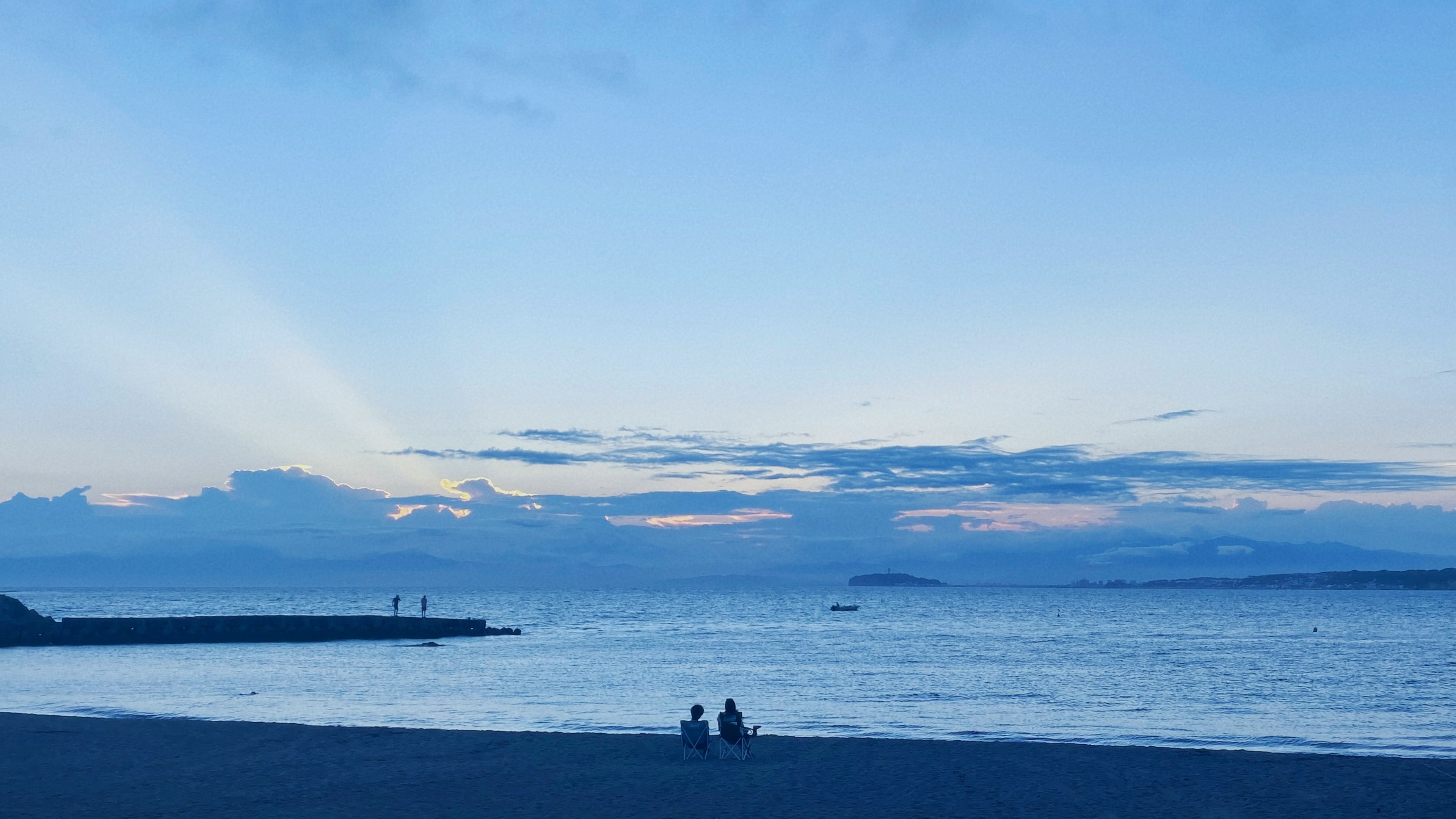 青い海と空の下で座る二人のシルエット