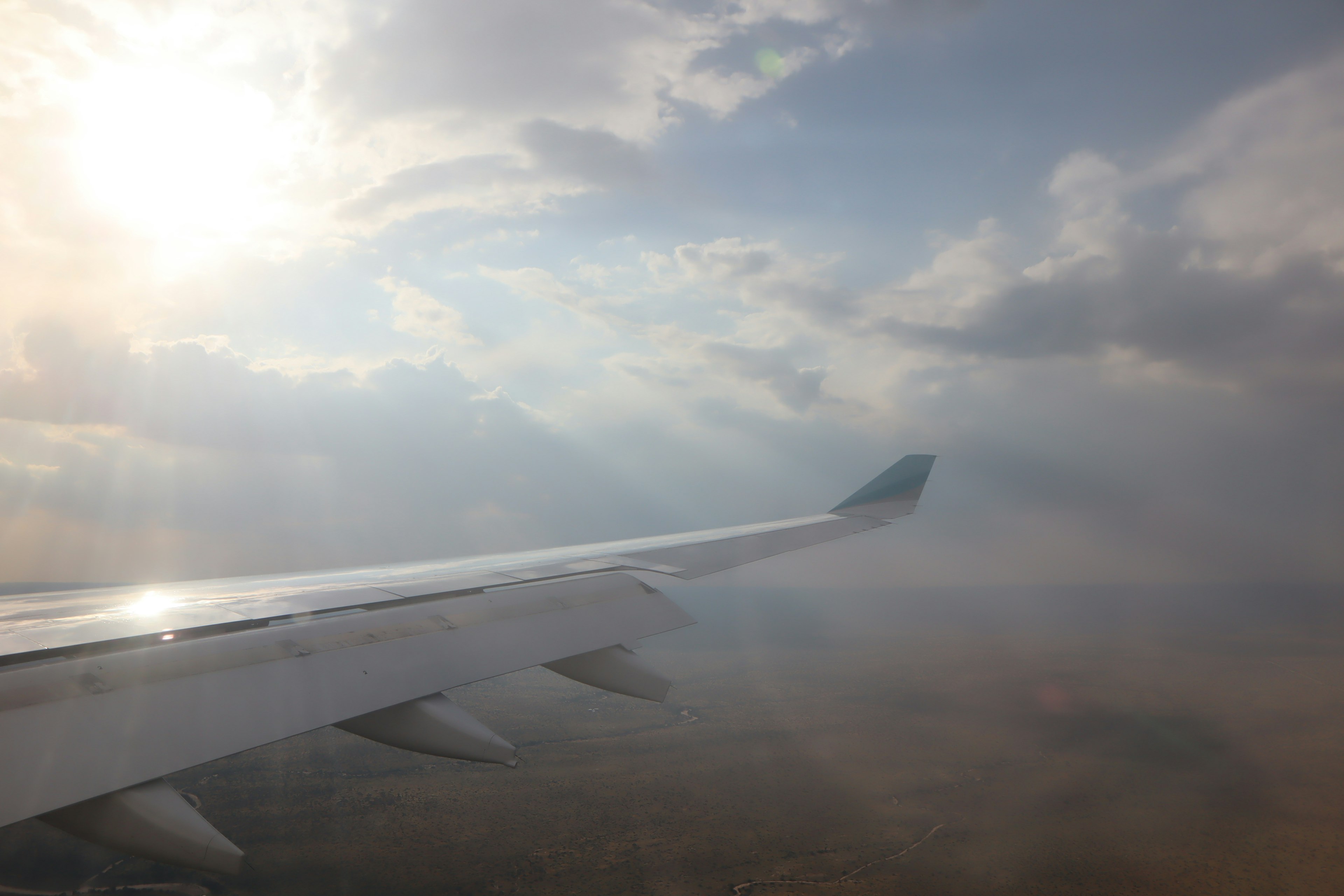 Imagen que muestra el ala de un avión con nubes y luz solar