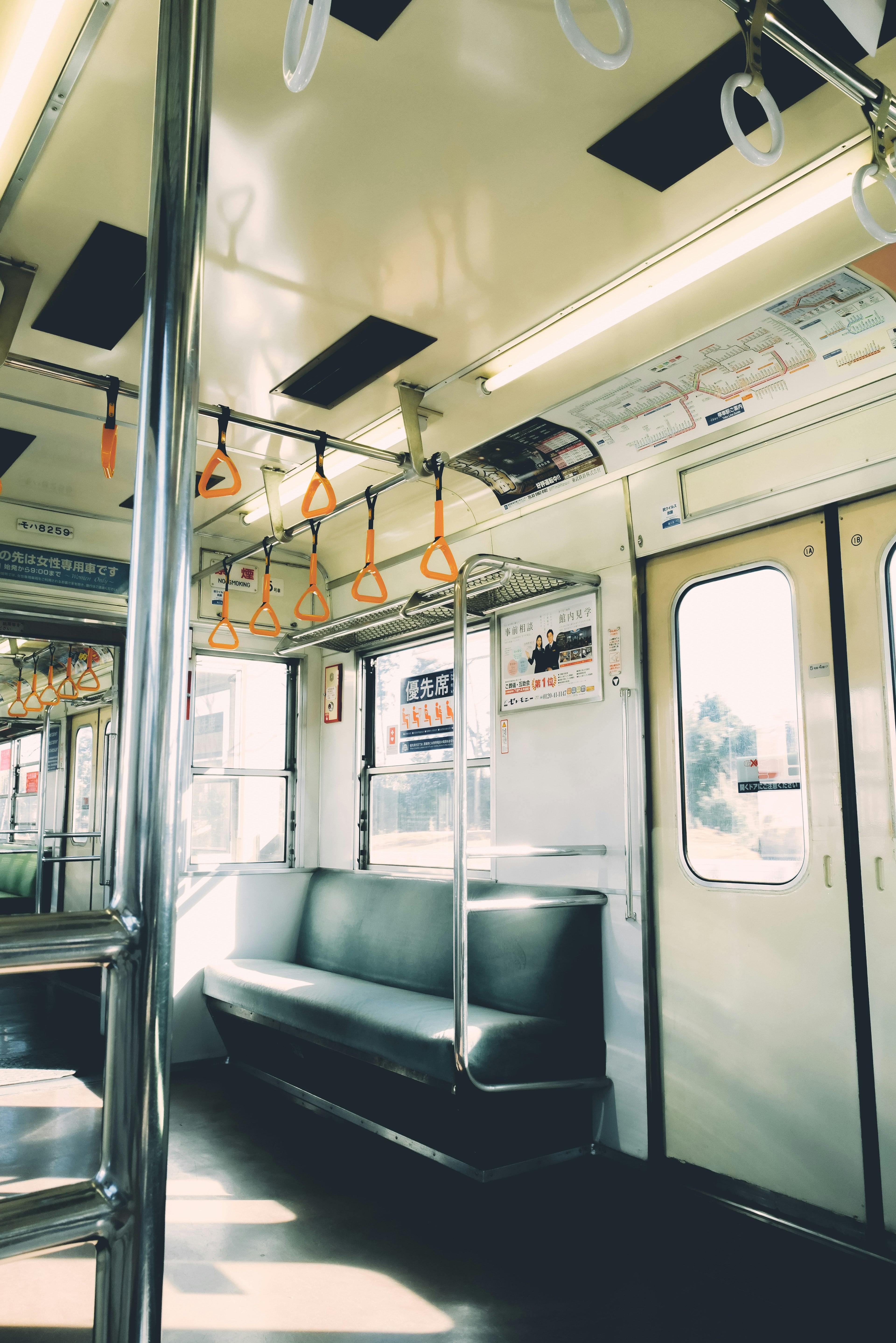 Interior of an empty subway train with green seats and sunlight streaming through the windows