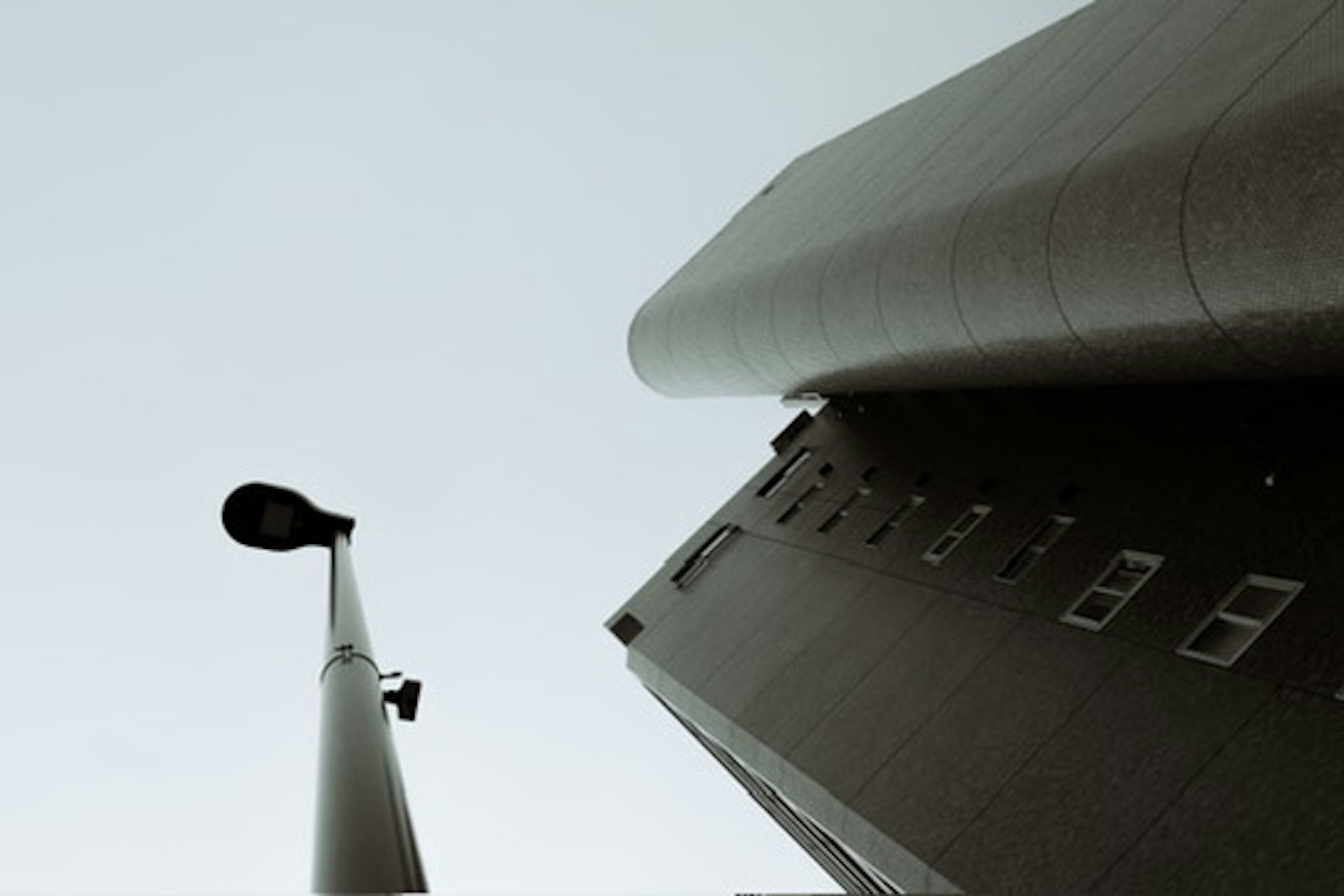 Photo prise d'en bas vers le haut d'un immeuble avec une façade grise et un lampadaire