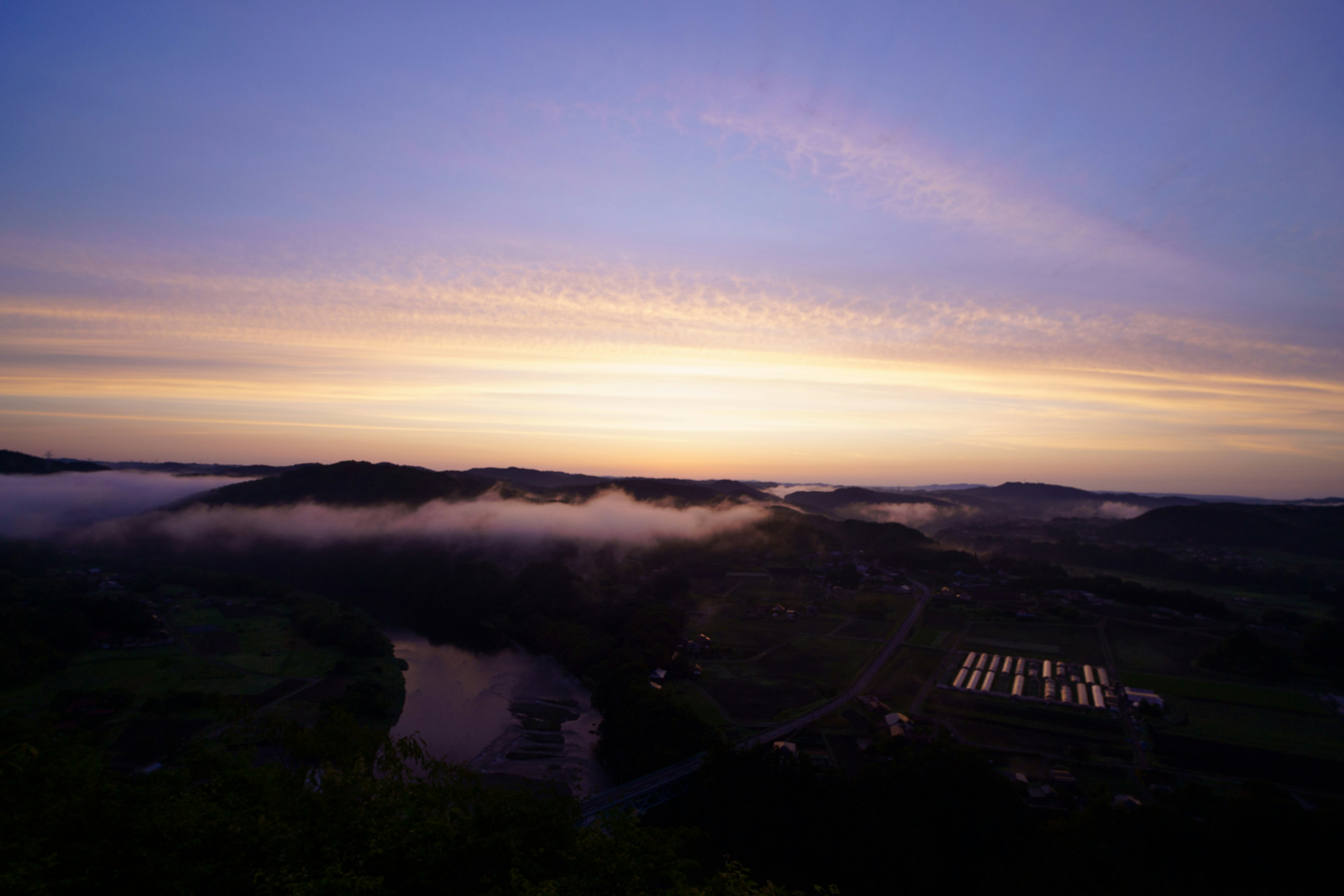 美しい夕暮れの風景、霧に包まれた谷と川、空に広がる柔らかな色合い