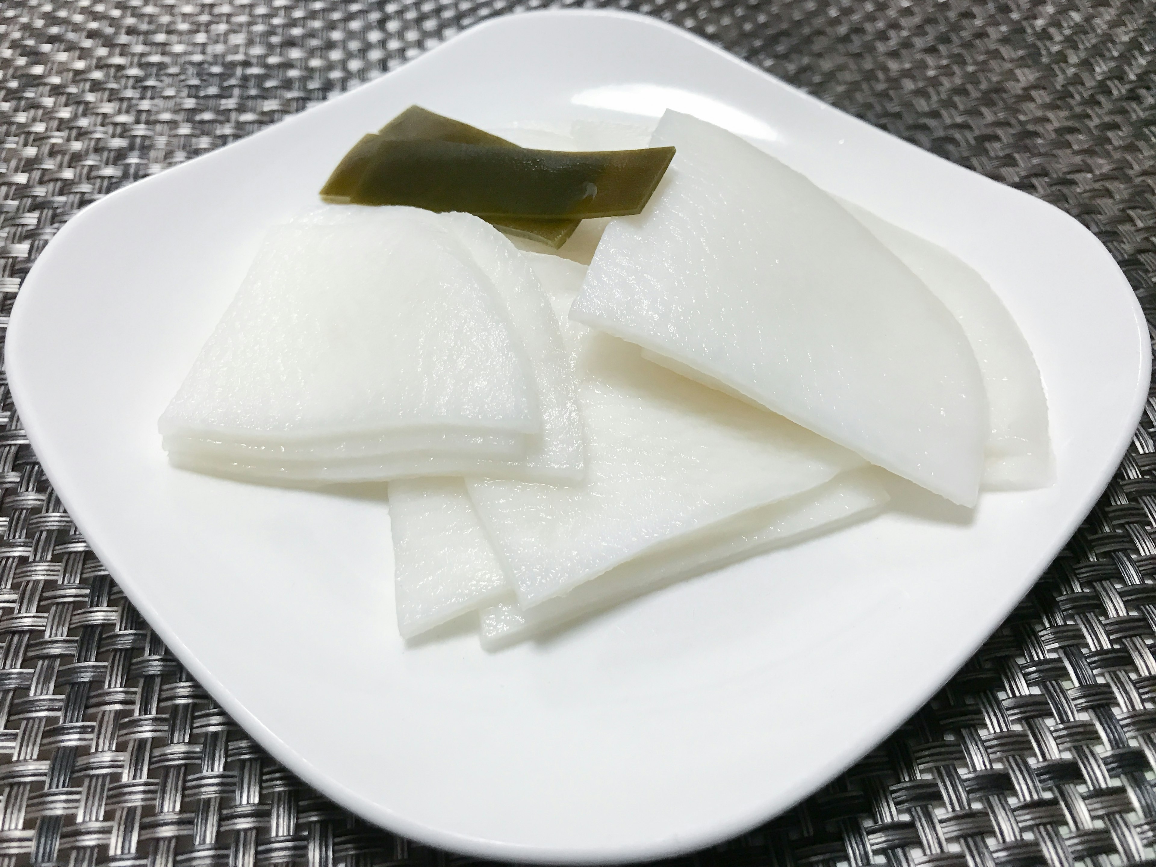 Slices of white radish and kelp arranged on a plate