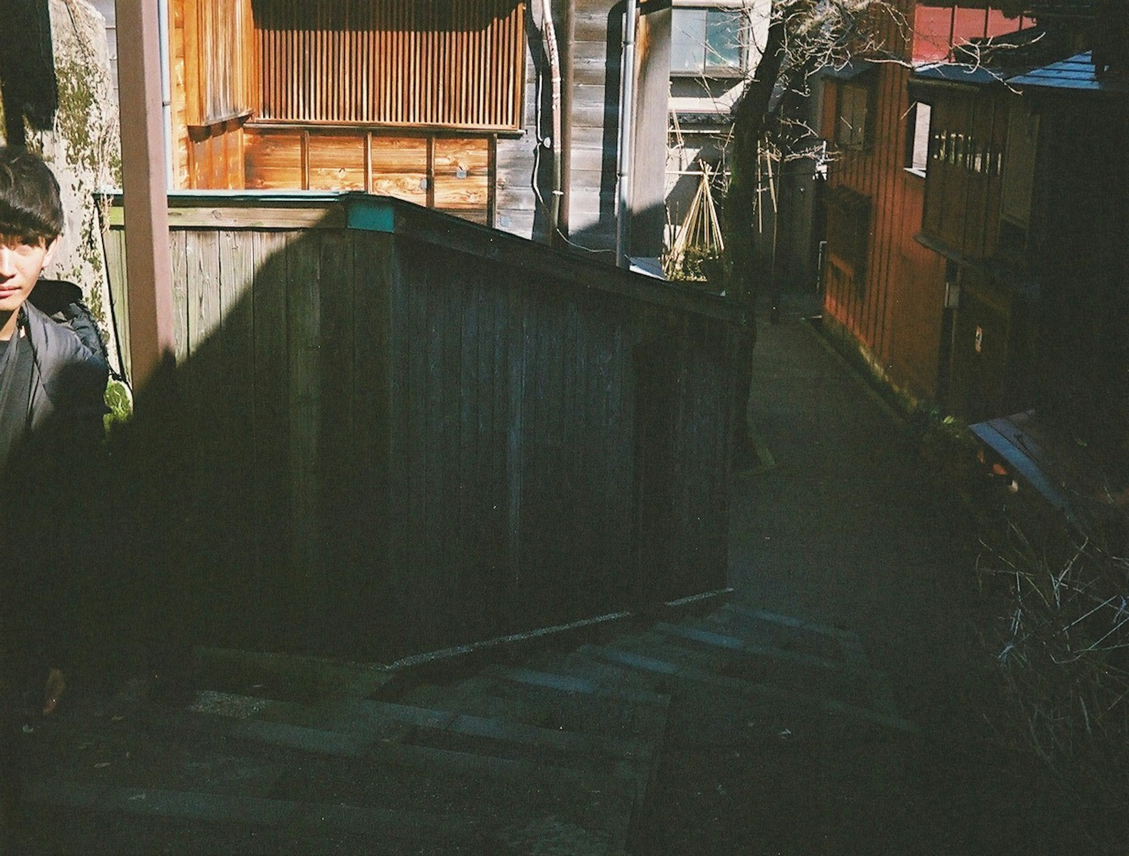 Man standing near a wooden staircase in a narrow alley