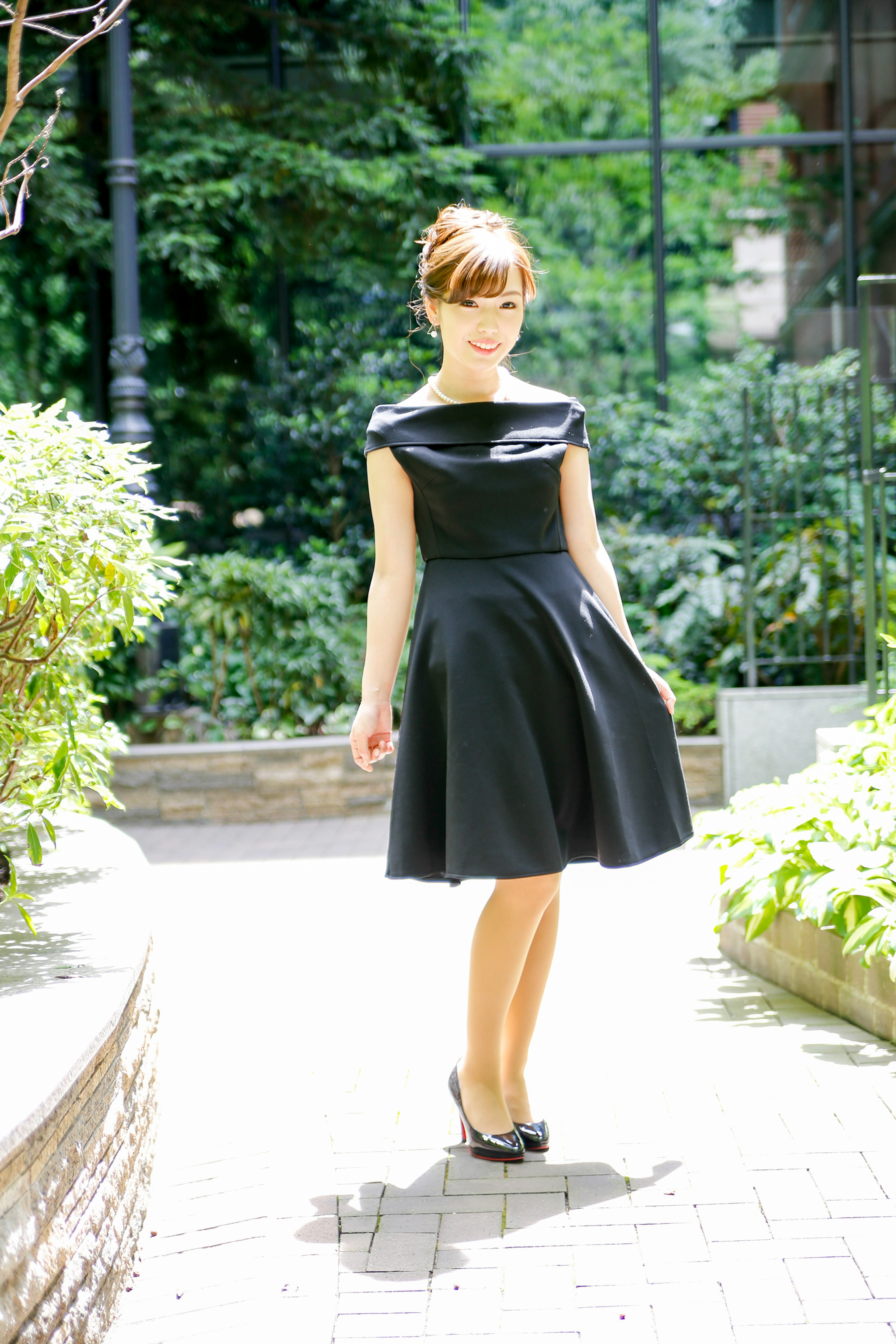 Une femme en robe noire pose dans un jardin