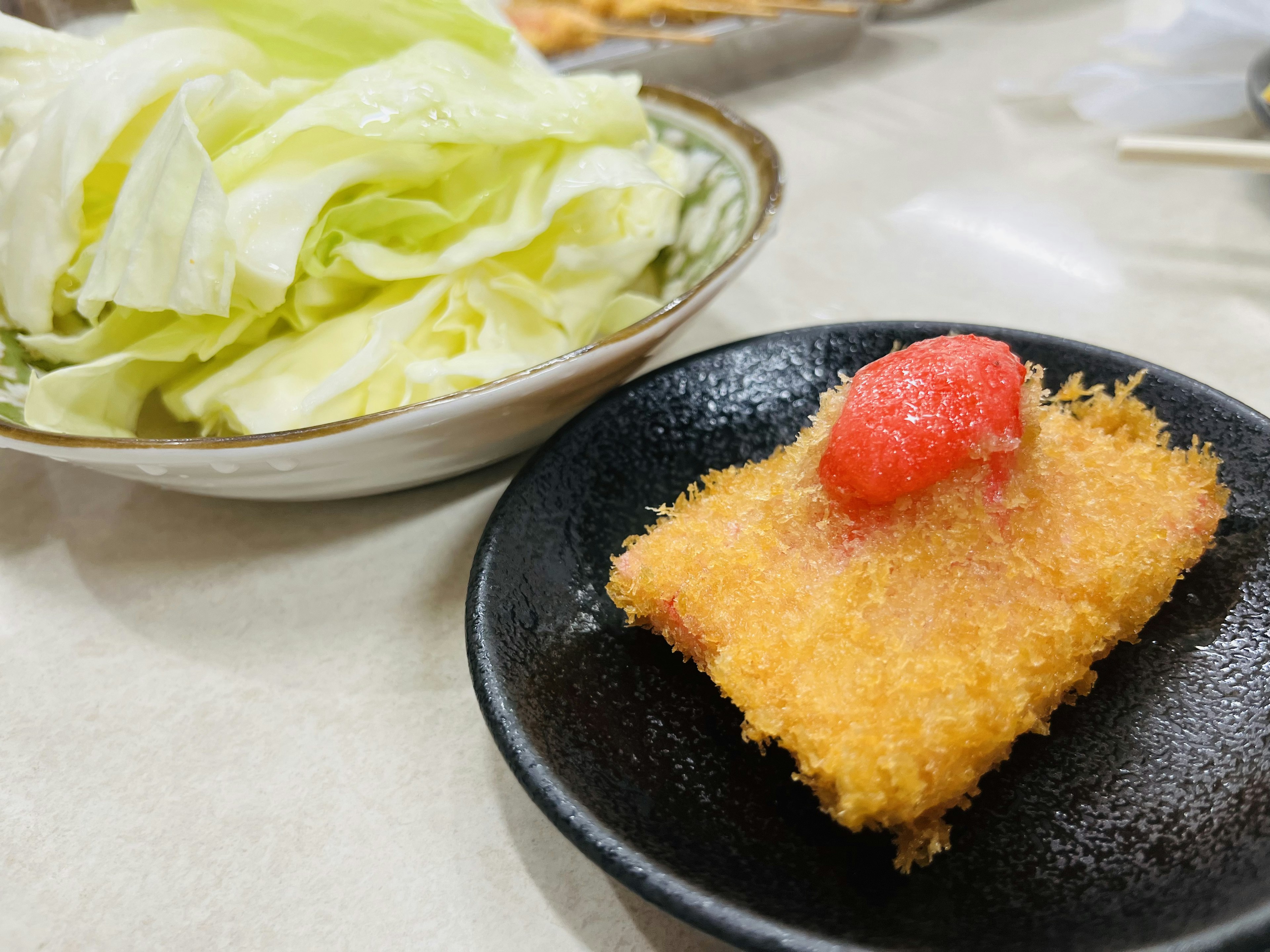 揚げた料理の上に赤いトマトがのった料理とサラダの皿