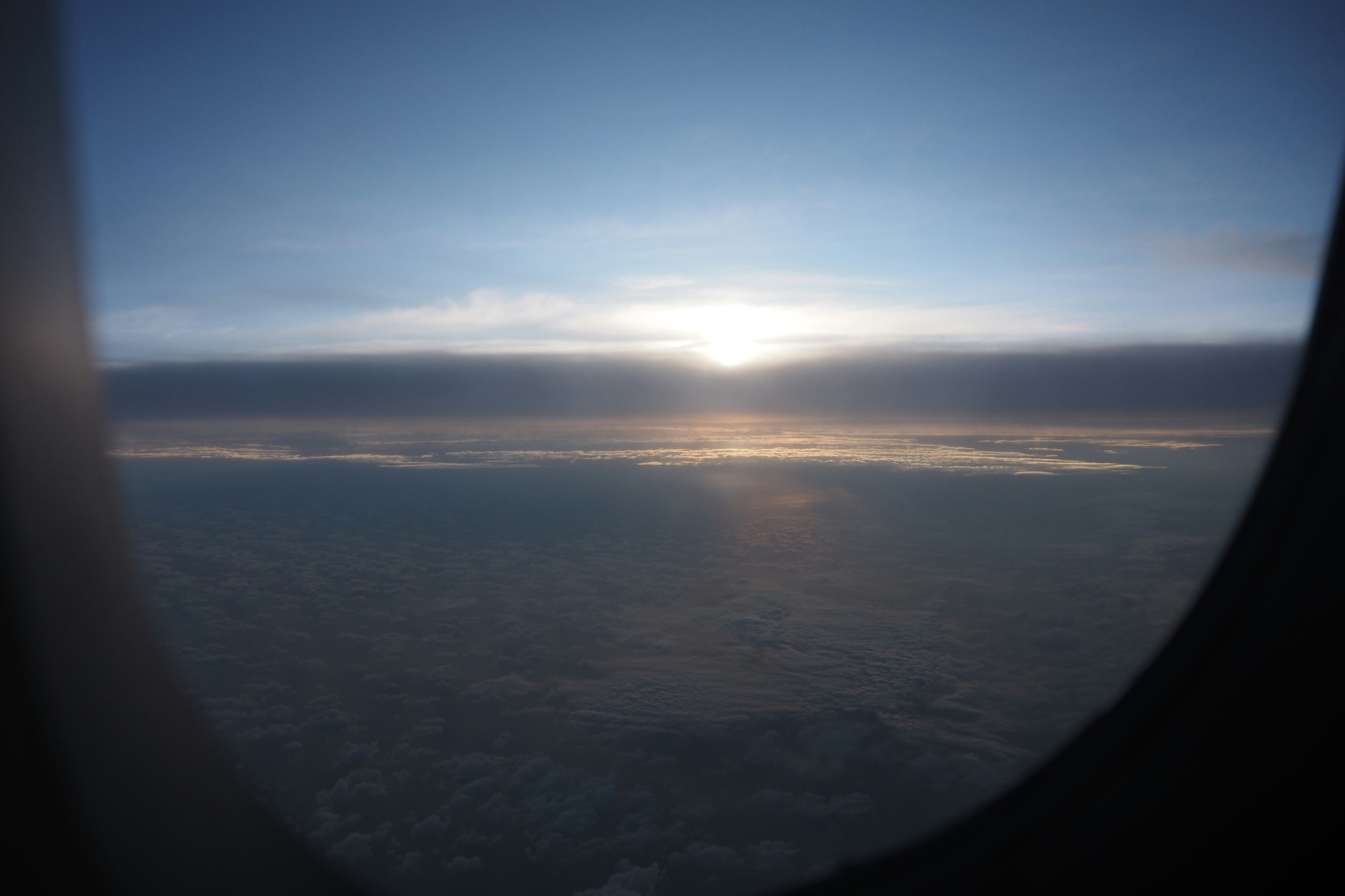 Sonnenuntergang und Wolken durch ein Flugzeugfenster gesehen