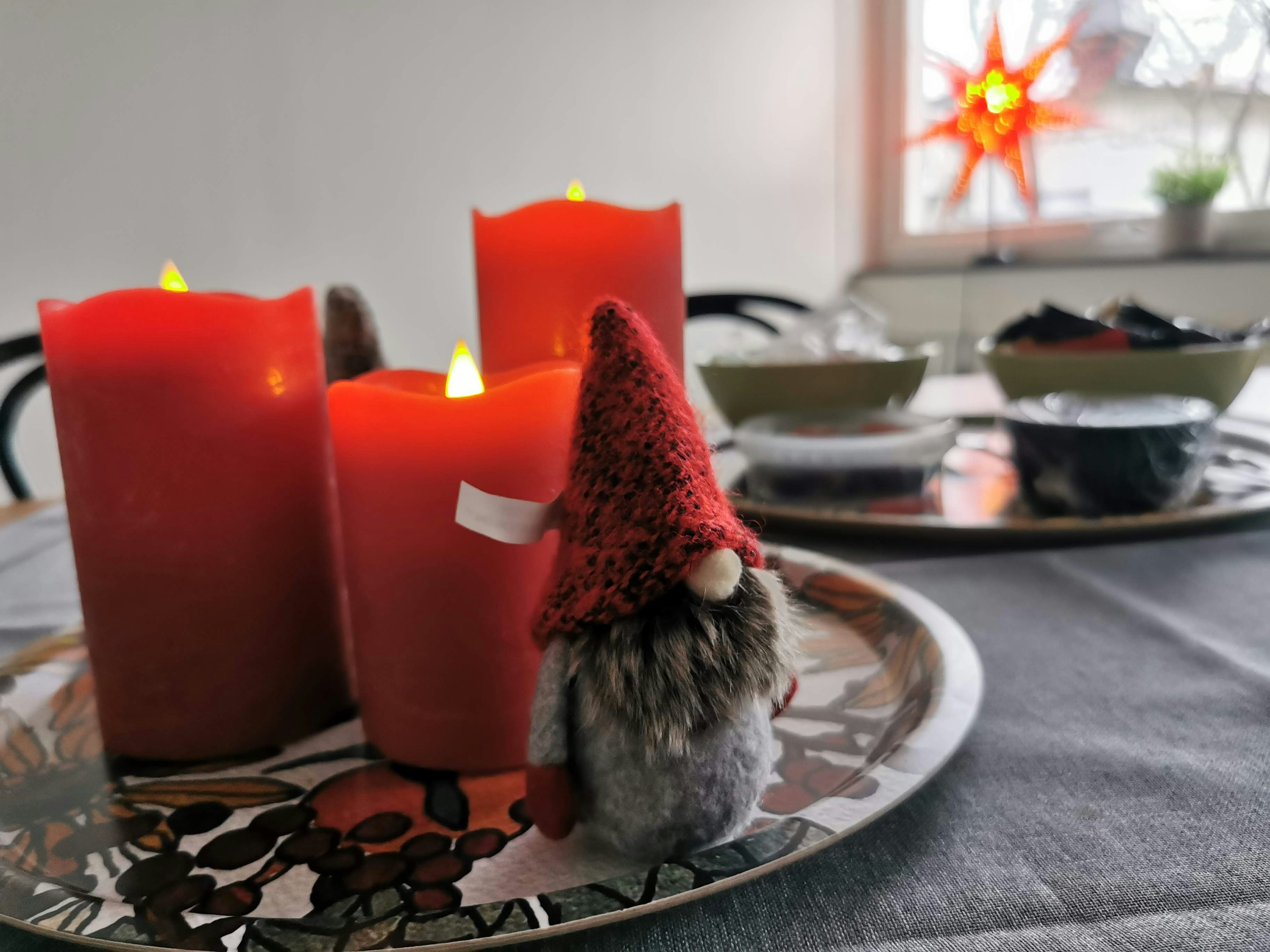 Szene mit roten Kerzen und einer kleinen Gnome-Figur auf einem Tisch