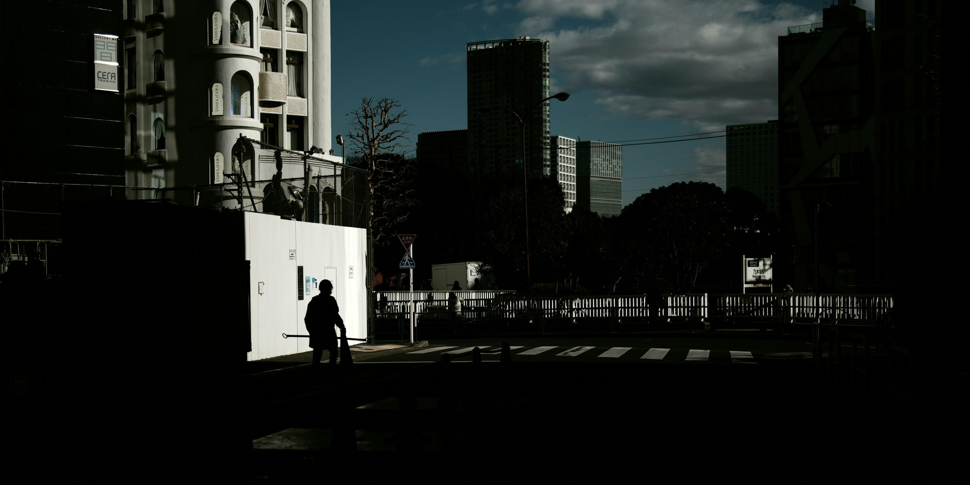 Silhouette of a person walking at an urban intersection with high-rise buildings