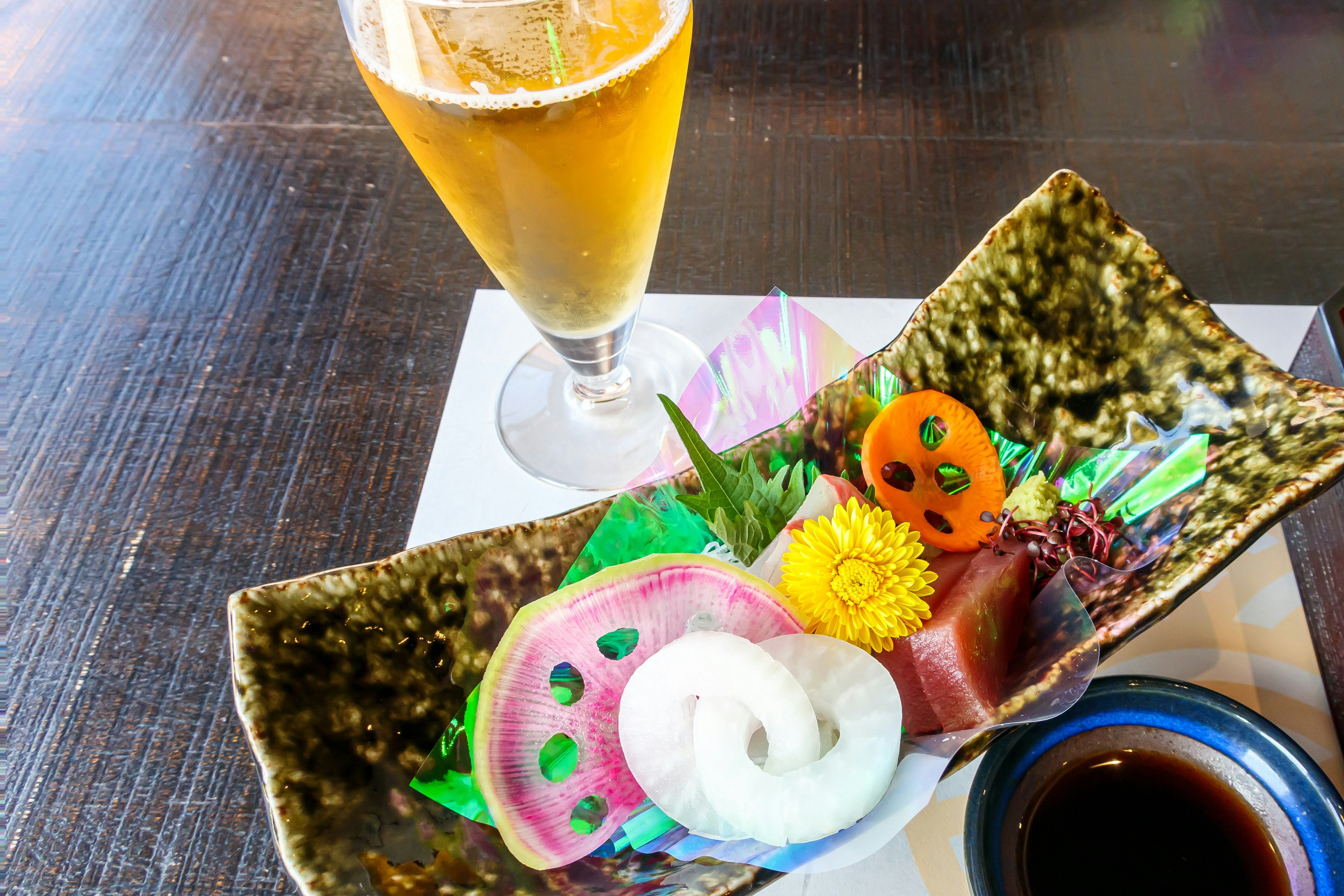 Une assiette de sashimi coloré avec une bière à côté