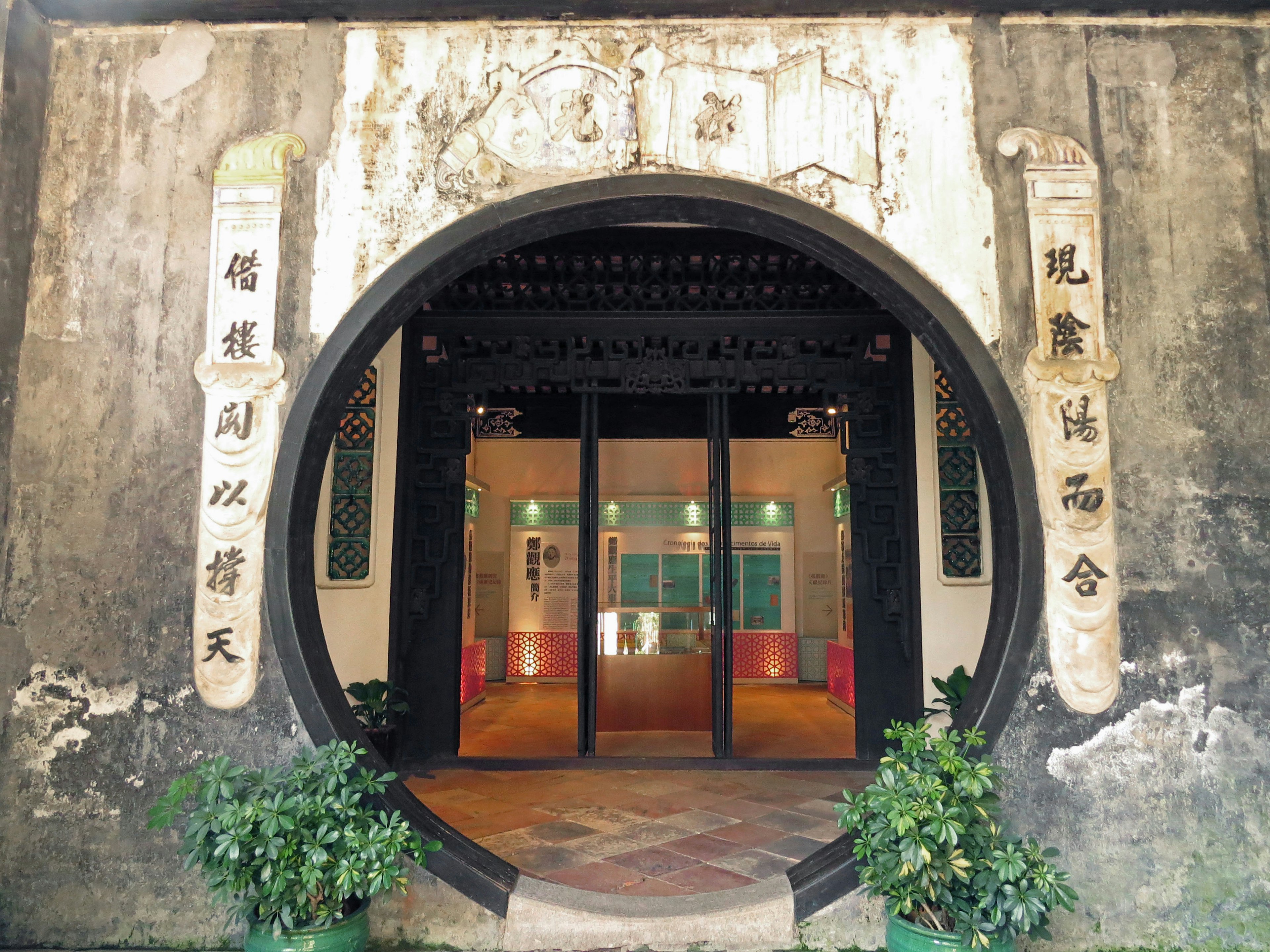 Circular entrance with traditional Chinese architectural style surrounded by green plants