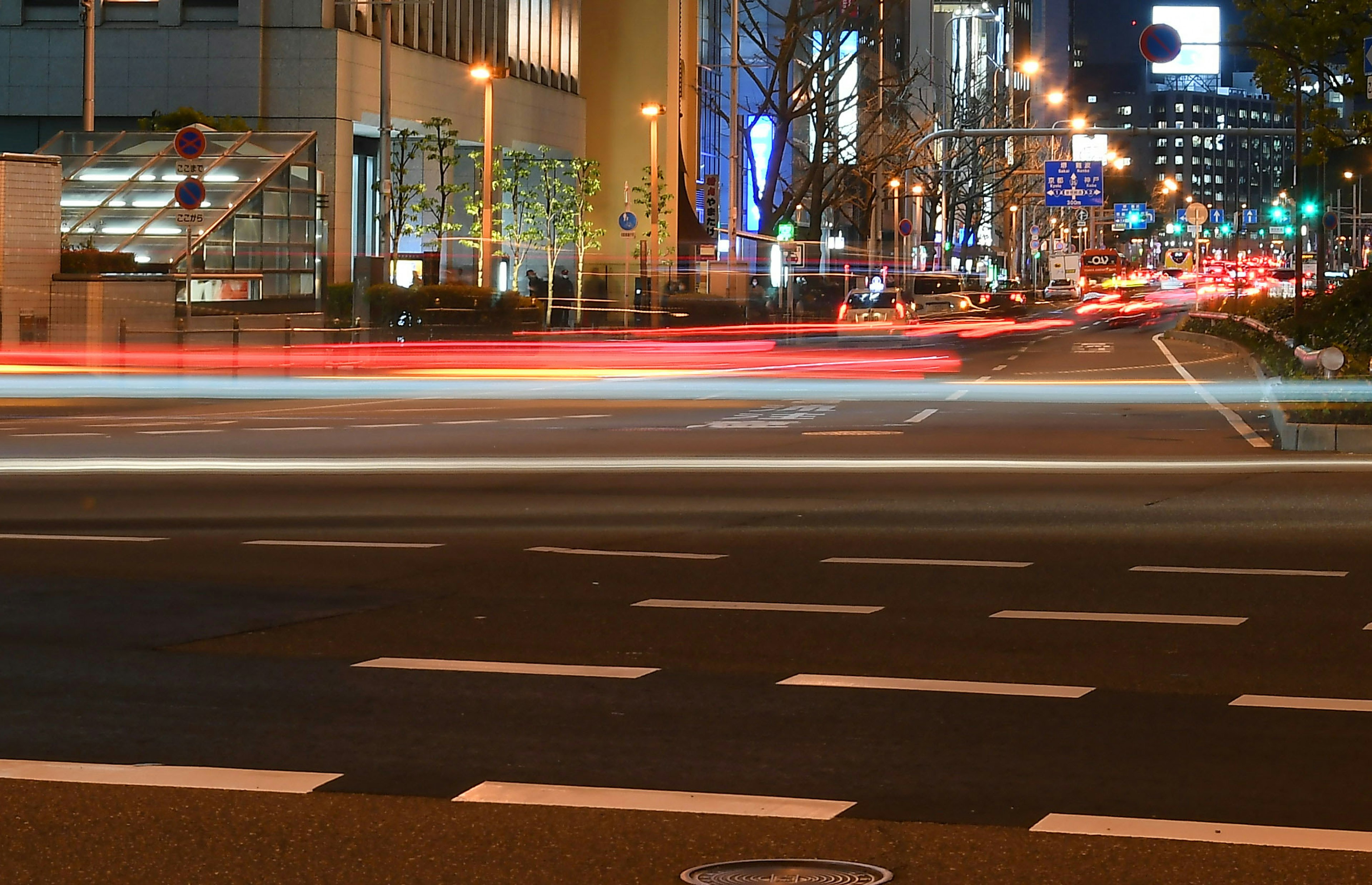 Light trails of cars at a city intersection at night with illuminated buildings