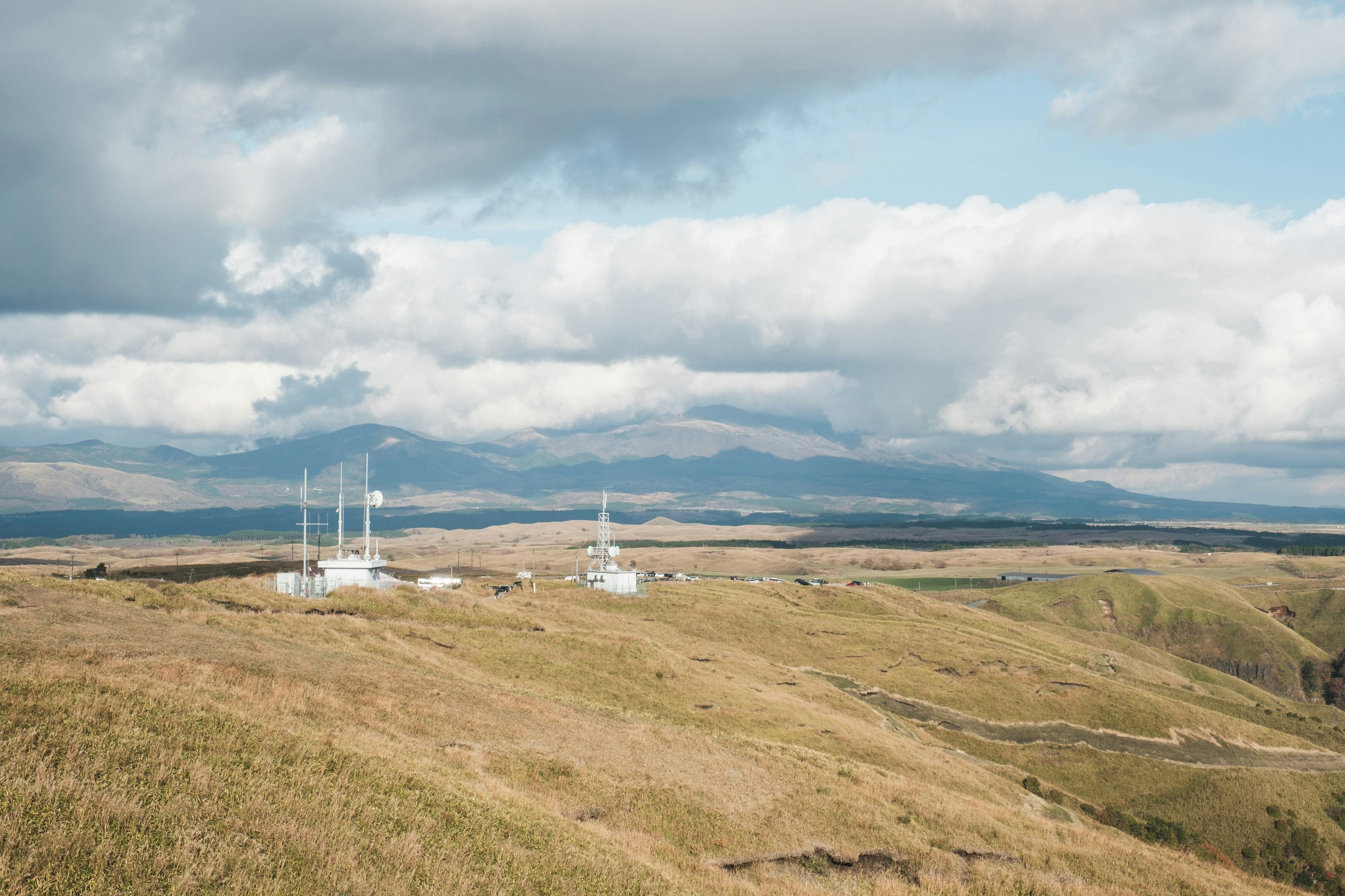 Collines ondulantes avec des tours de communication blanches sous un ciel nuageux