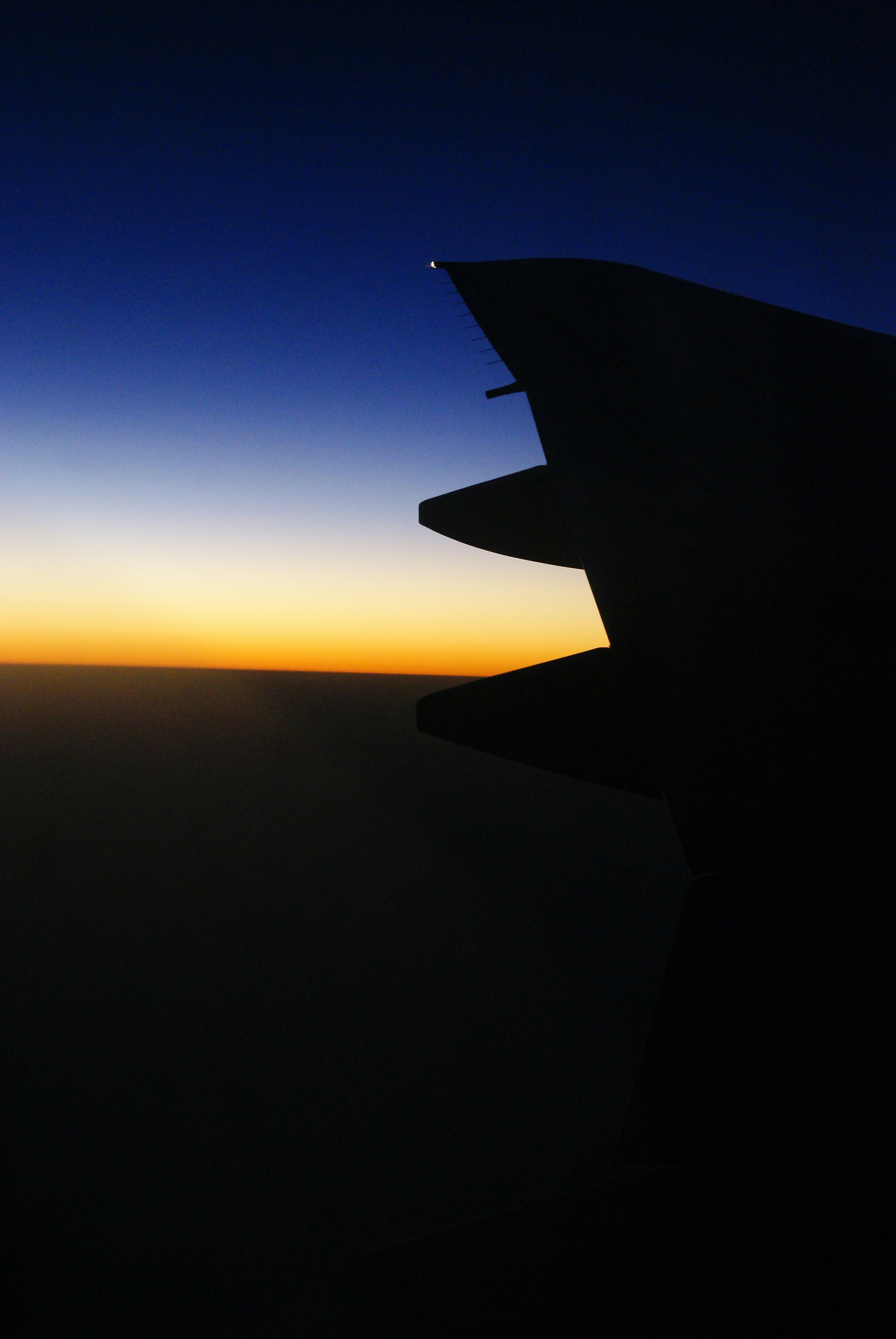 Silhouette of an airplane wing against a sunset sky