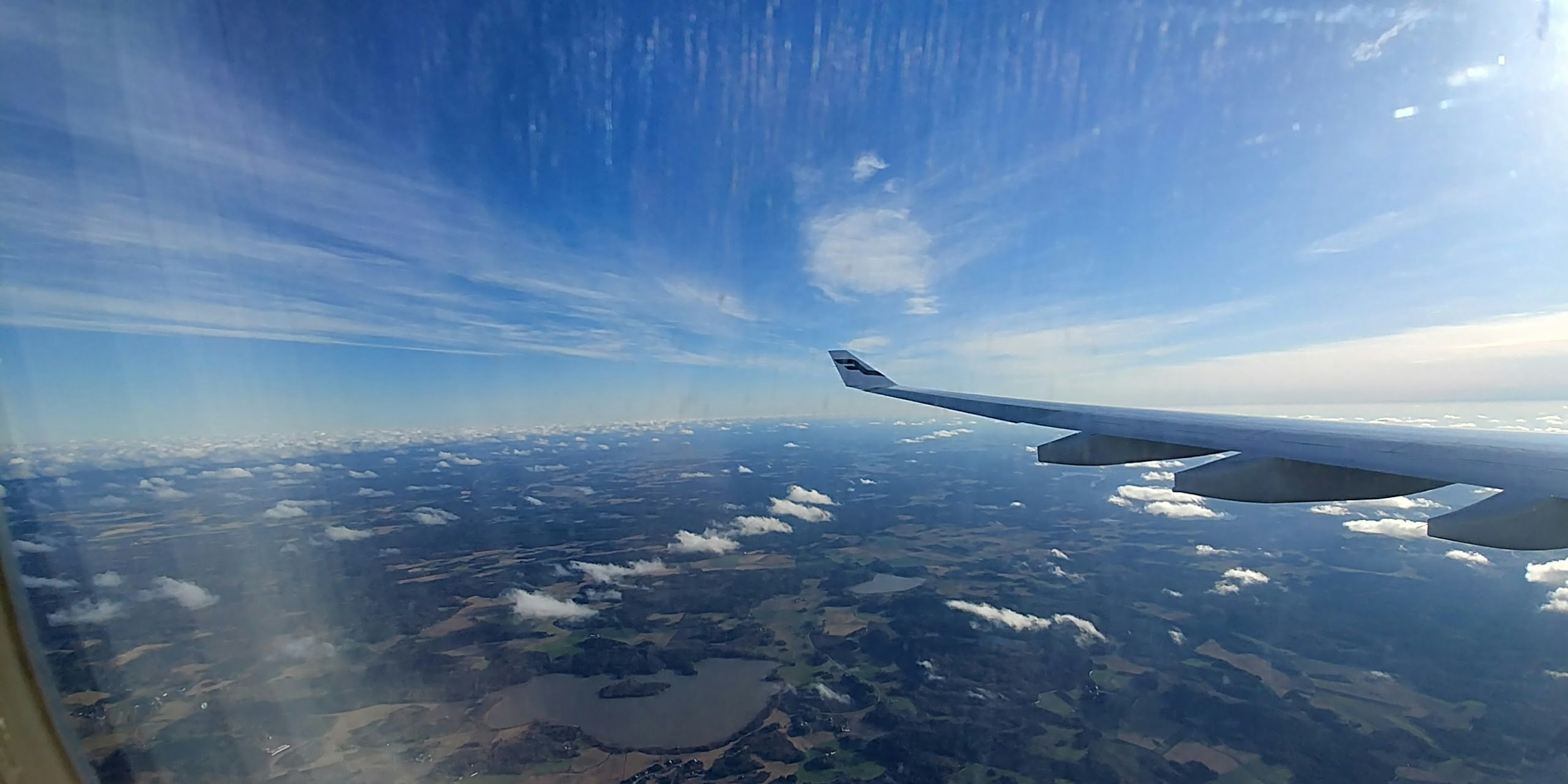 Flügel eines Flugzeugs vor blauem Himmel und Wolken