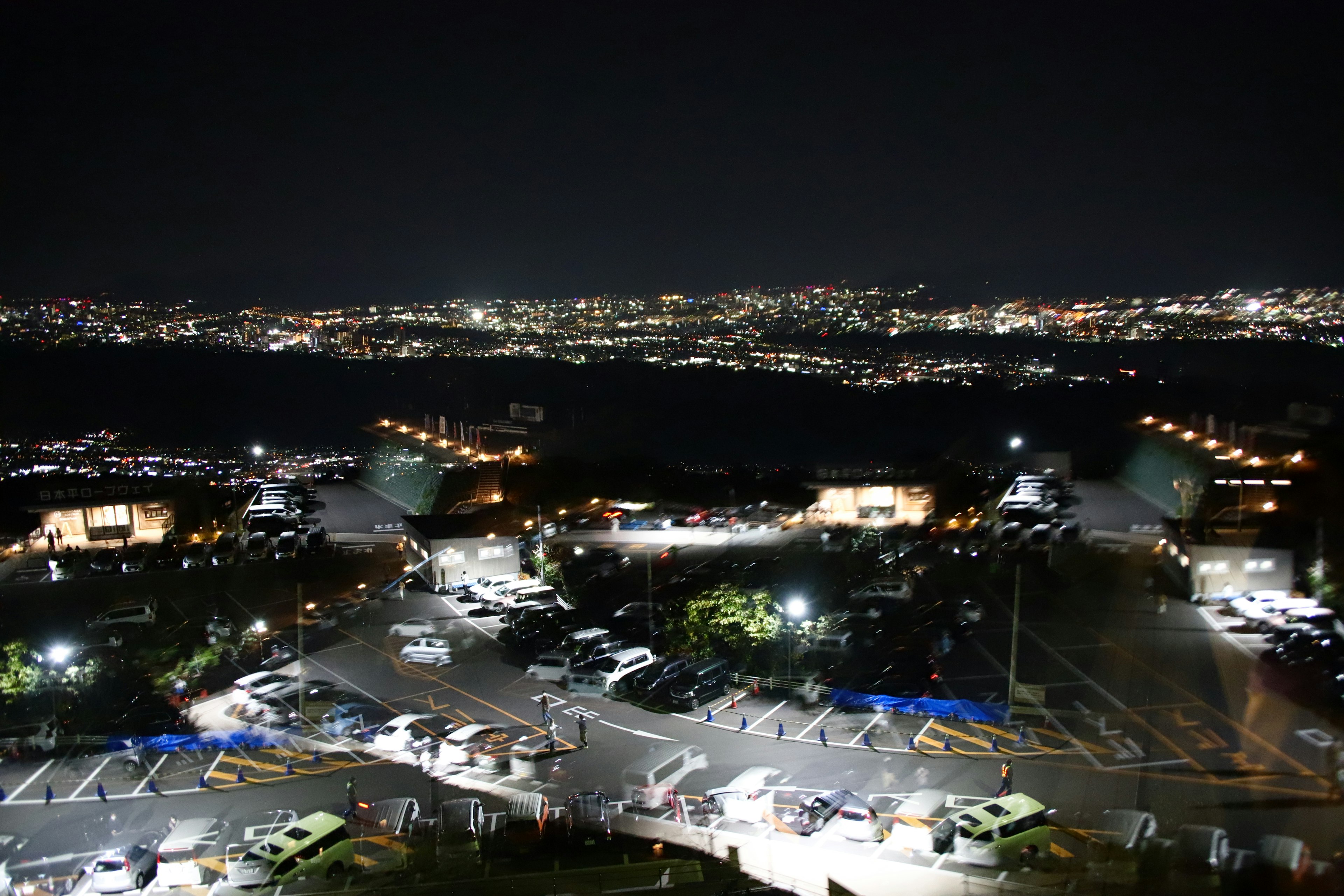 Vista nocturna de un estacionamiento con luces de la ciudad de fondo