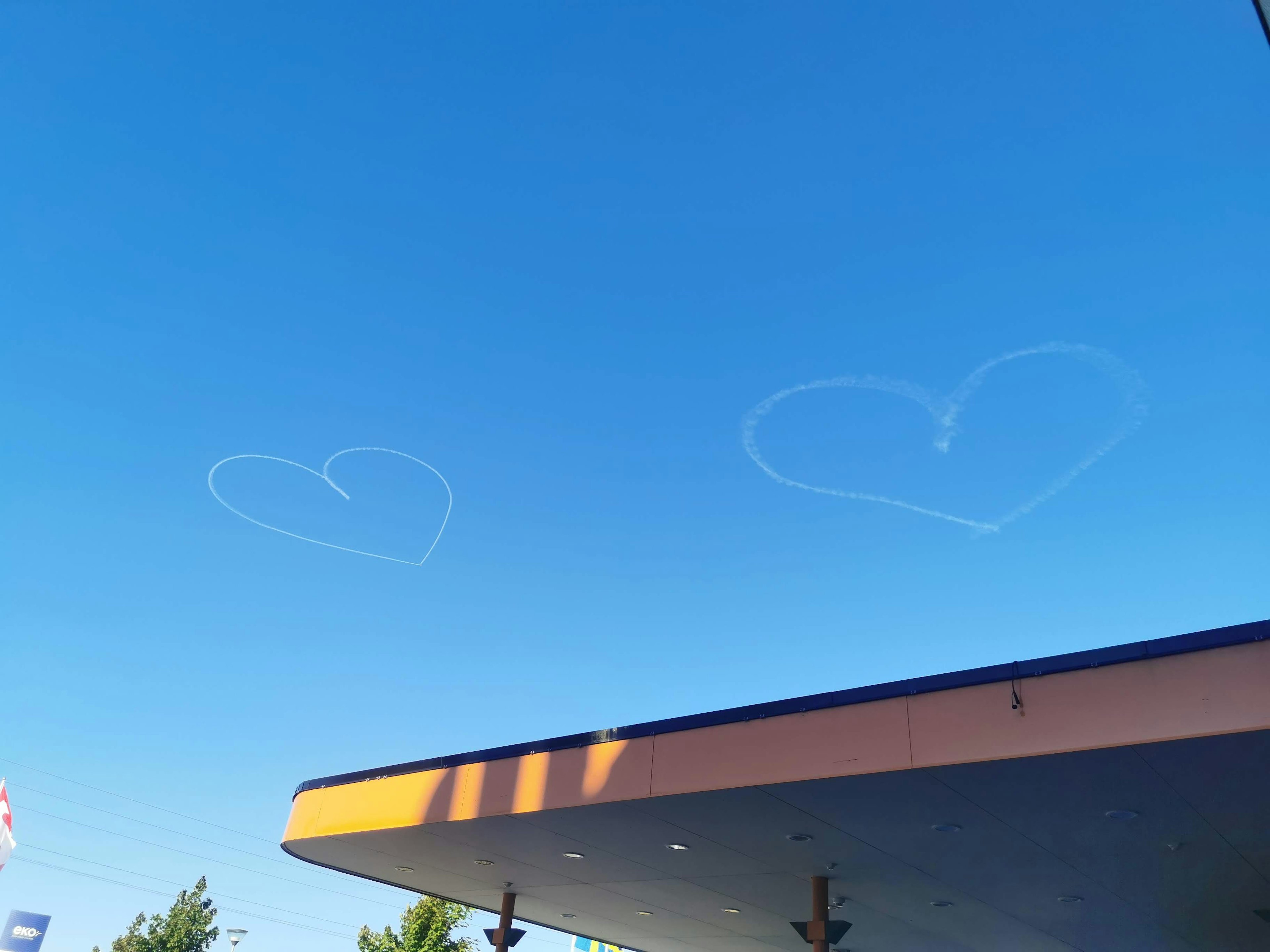 Estelas de avión en forma de corazón en un cielo azul con un techo de edificio