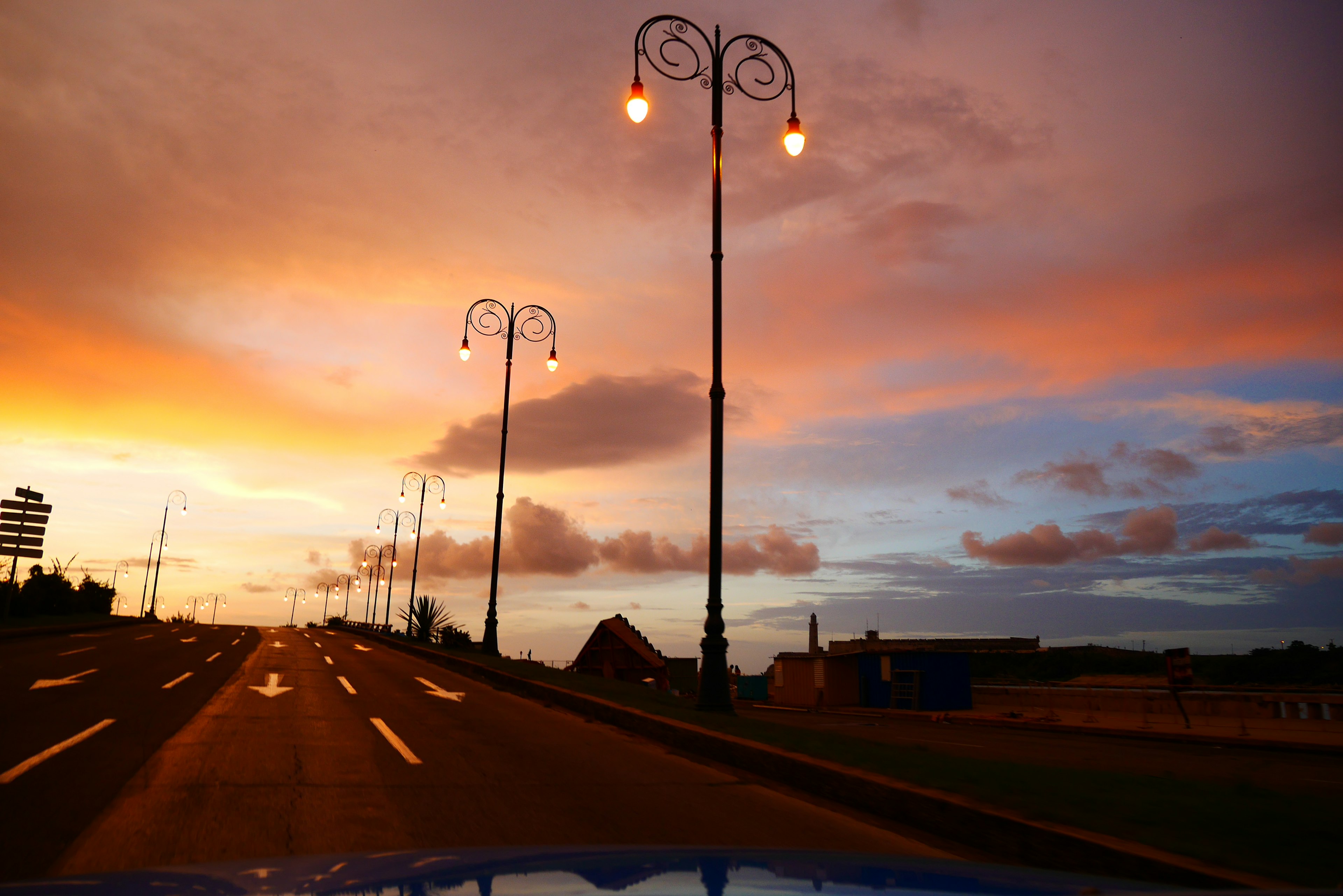 Route avec des lampadaires sous un ciel coloré au coucher du soleil