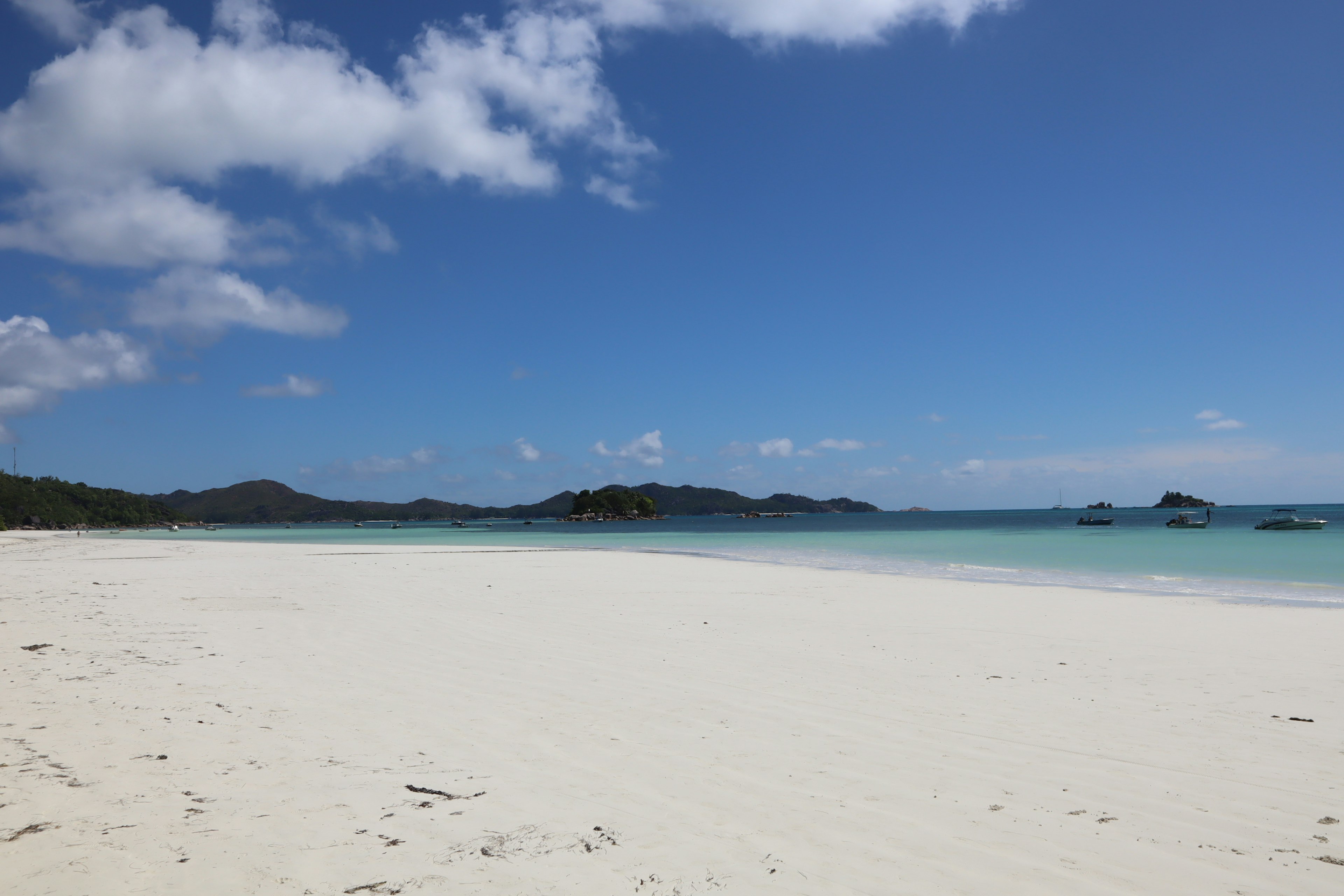 ทิวทัศน์ชายหาดที่สวยงามพร้อมท้องฟ้าสีฟ้าและชายฝั่งทรายขาว