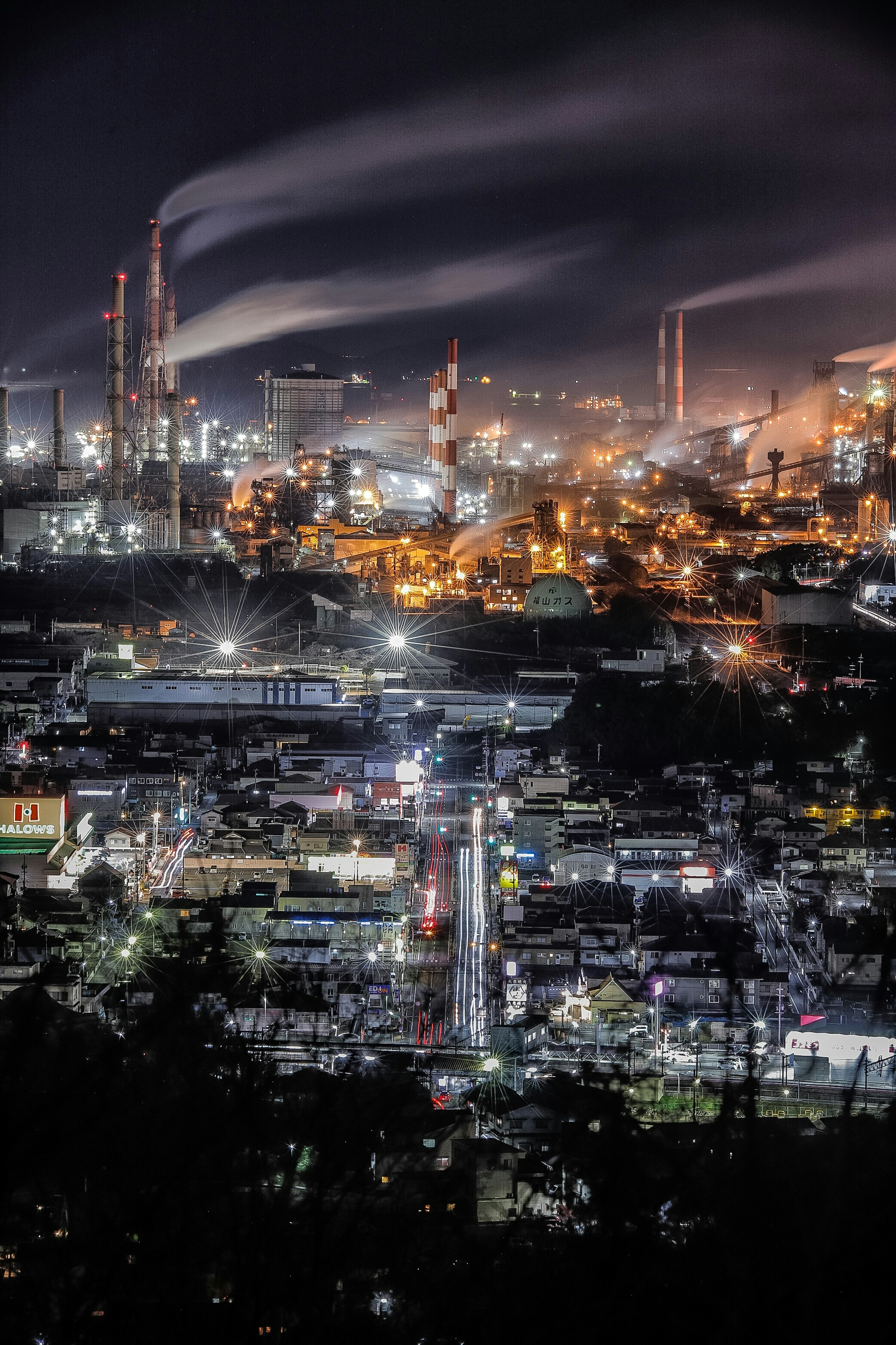 Vista notturna di un'area industriale con fumi da camini luci di fabbrica brillanti e paesaggio urbano