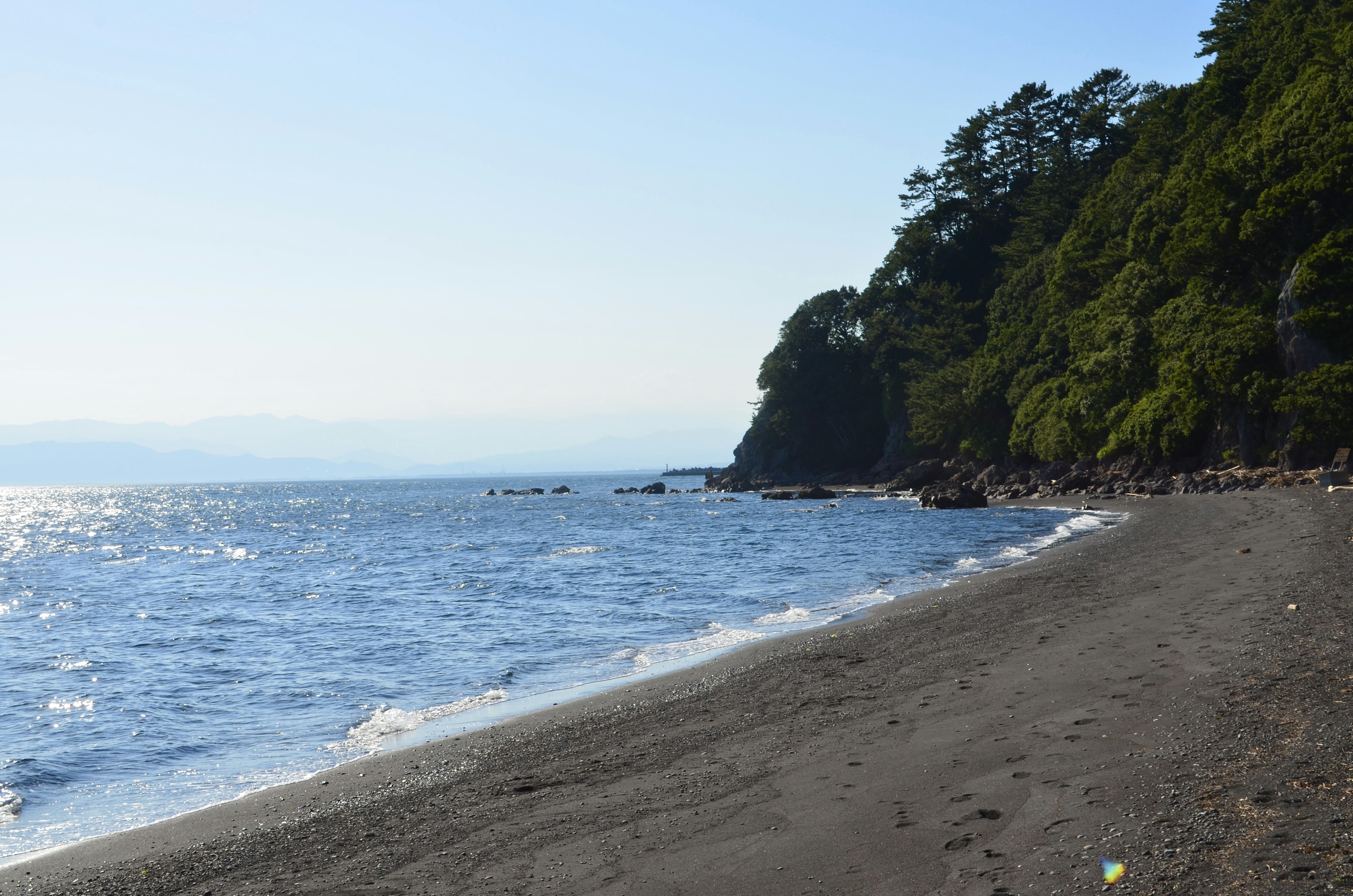 Eine ruhige Strandlandschaft mit Ozeanwellen und grünen Klippen