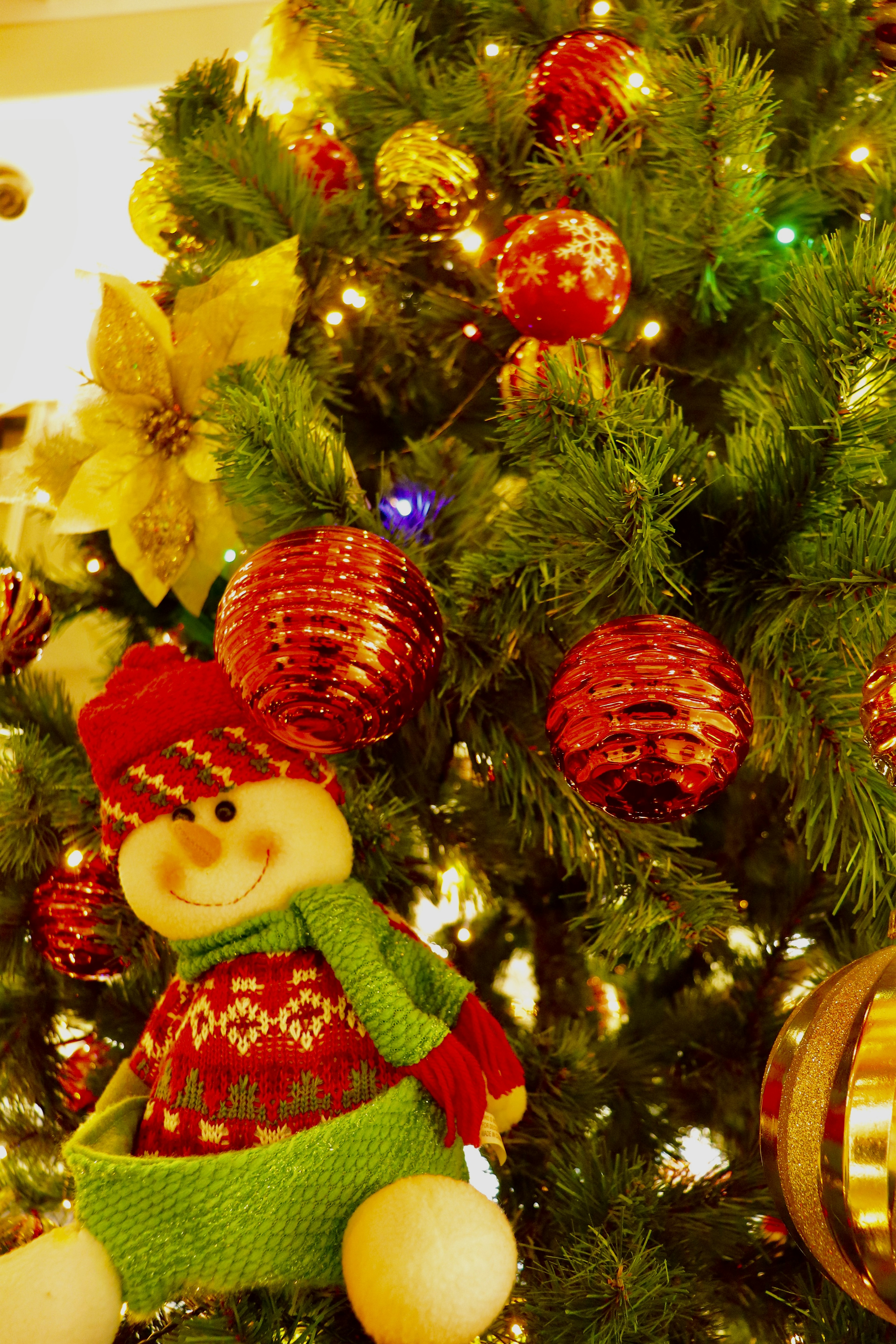 Christmas tree adorned with red and green ornaments and a snowman decoration