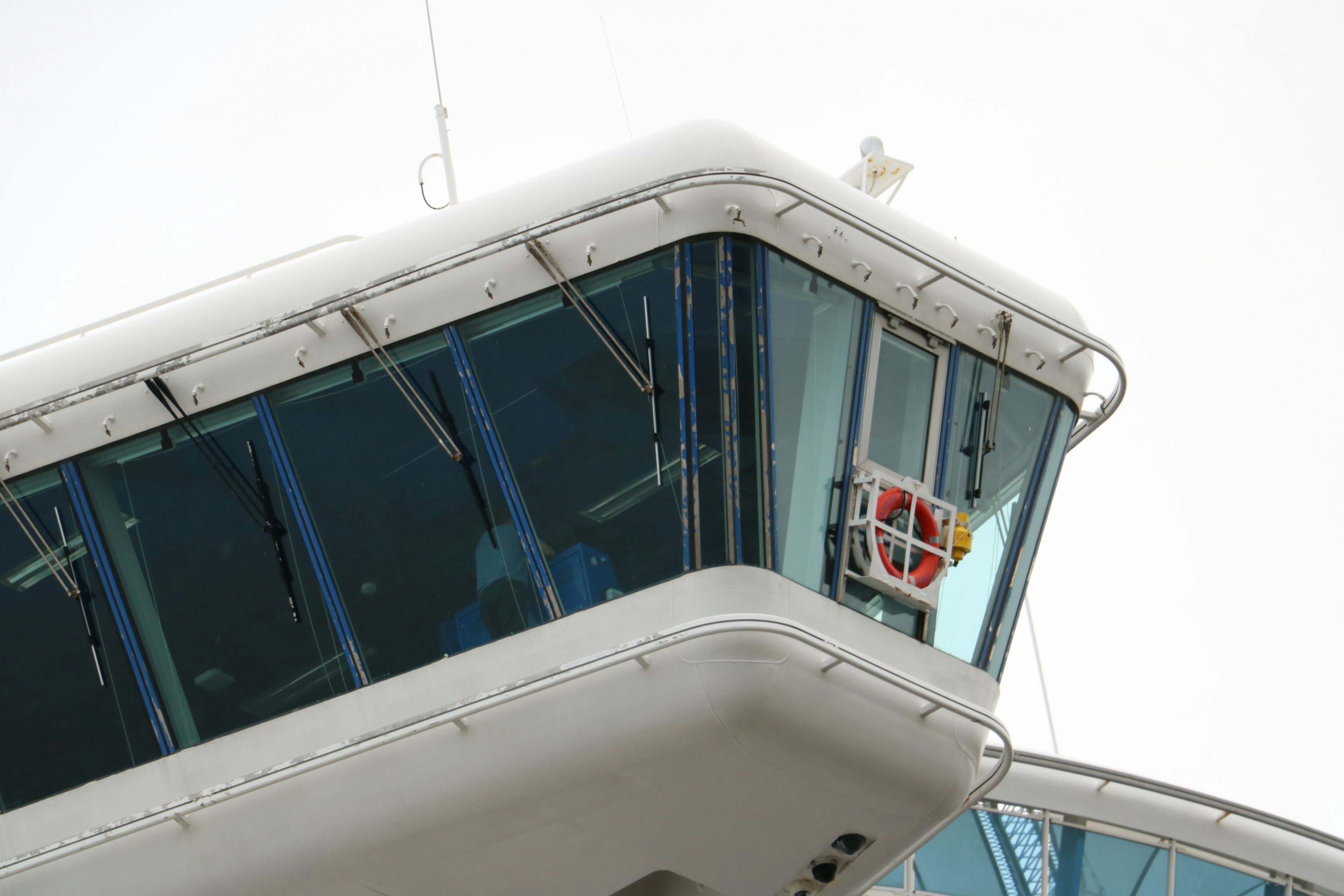 Imagen que muestra parte de una torre de control de aeropuerto con ventanas de vidrio y una estructura blanca