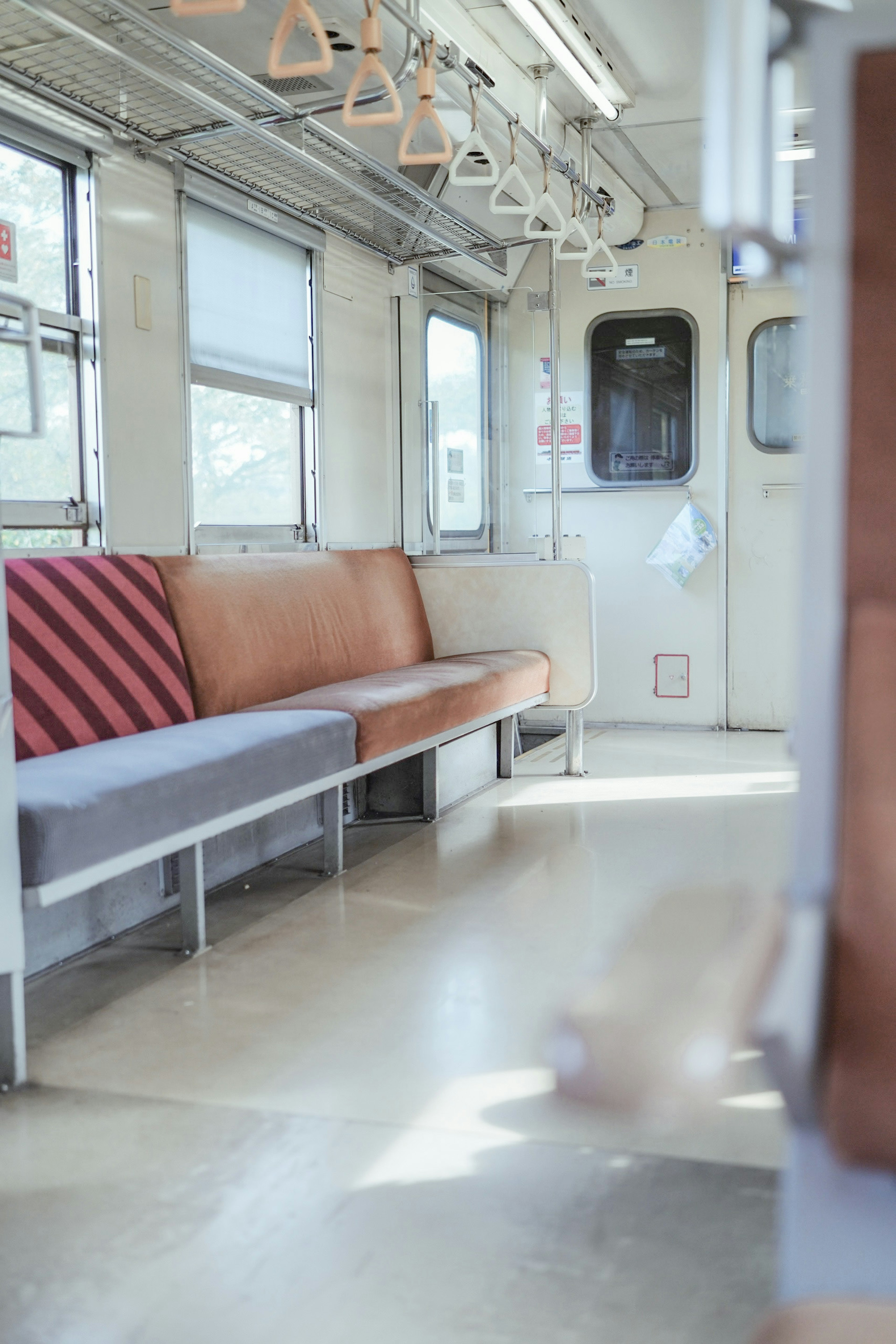 Interno di un vagone del treno quasi vuoto con panche e maniglie