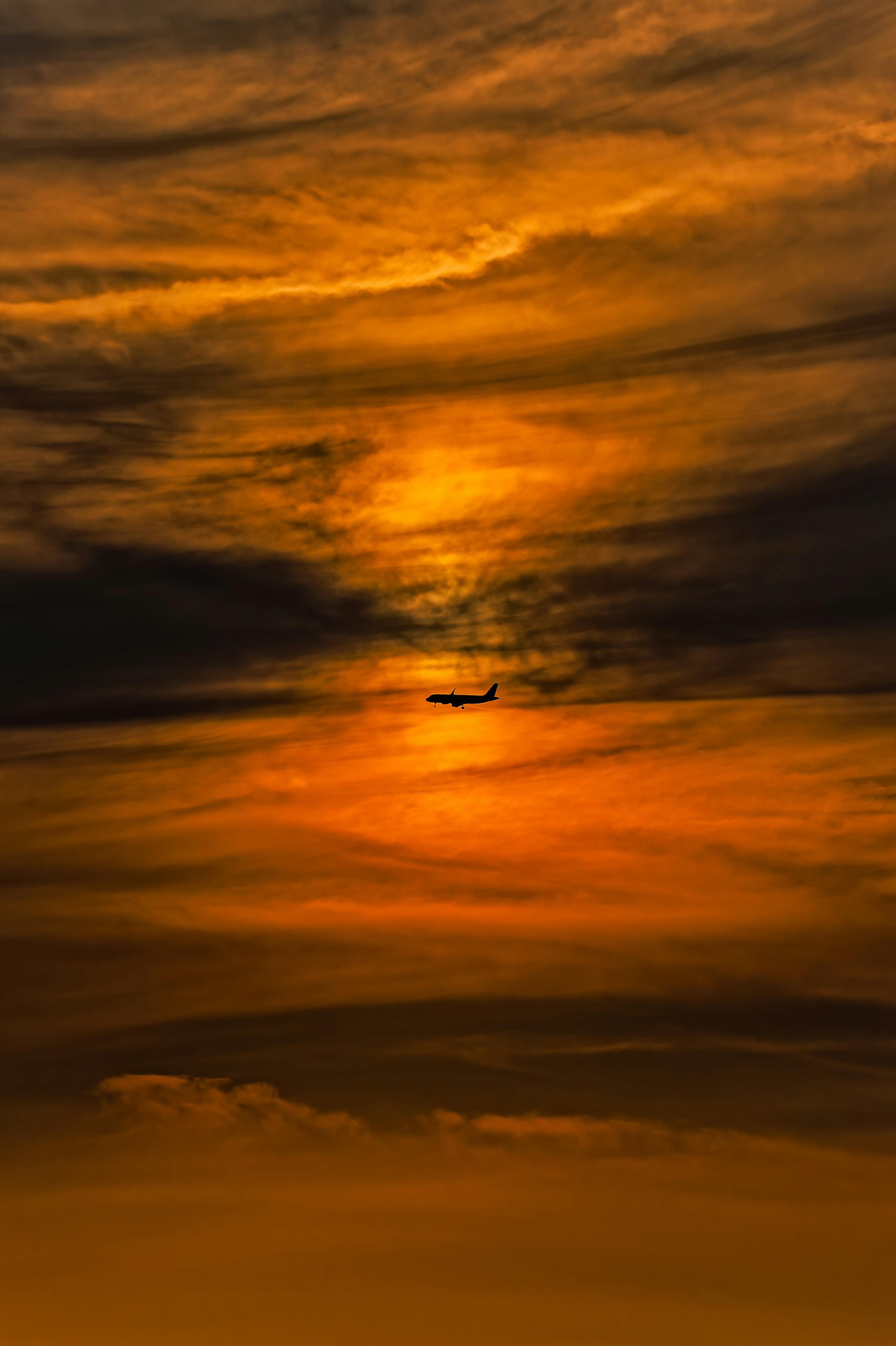 夕焼けの空に浮かぶ飛行機のシルエット