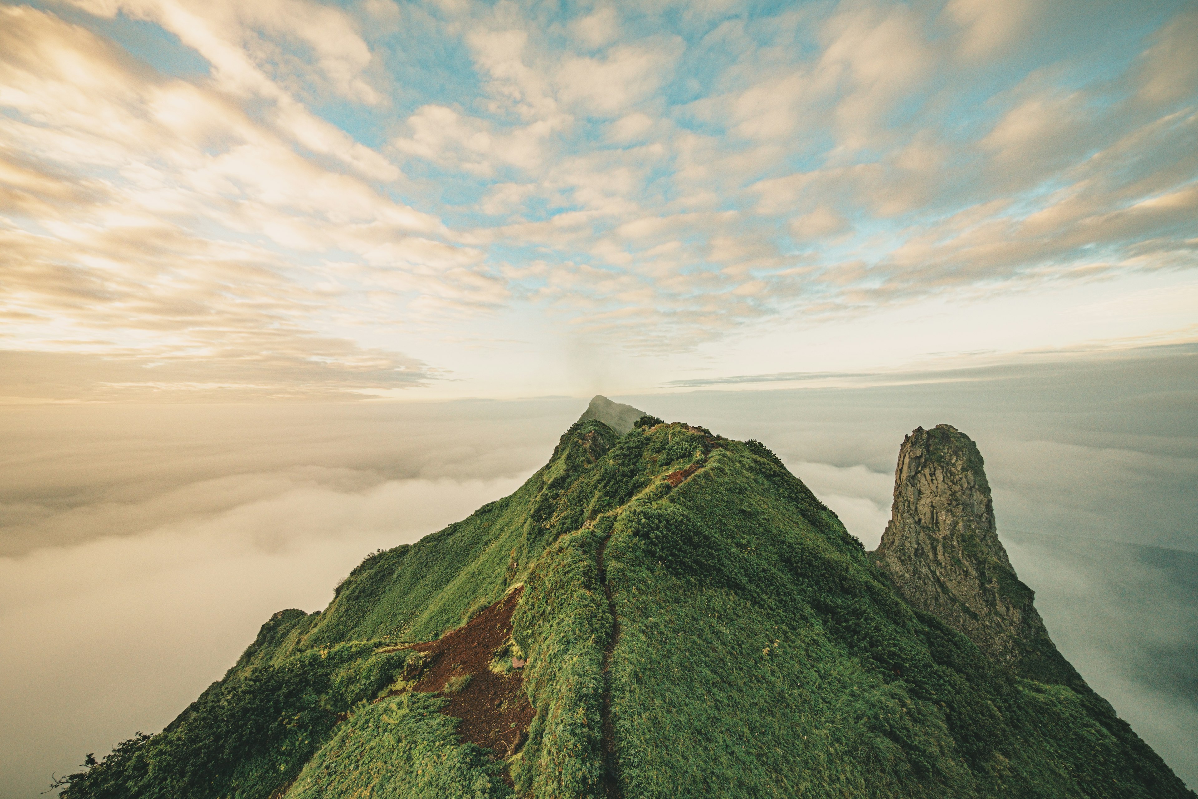 青い空と雲に囲まれた緑豊かな山の峰風景