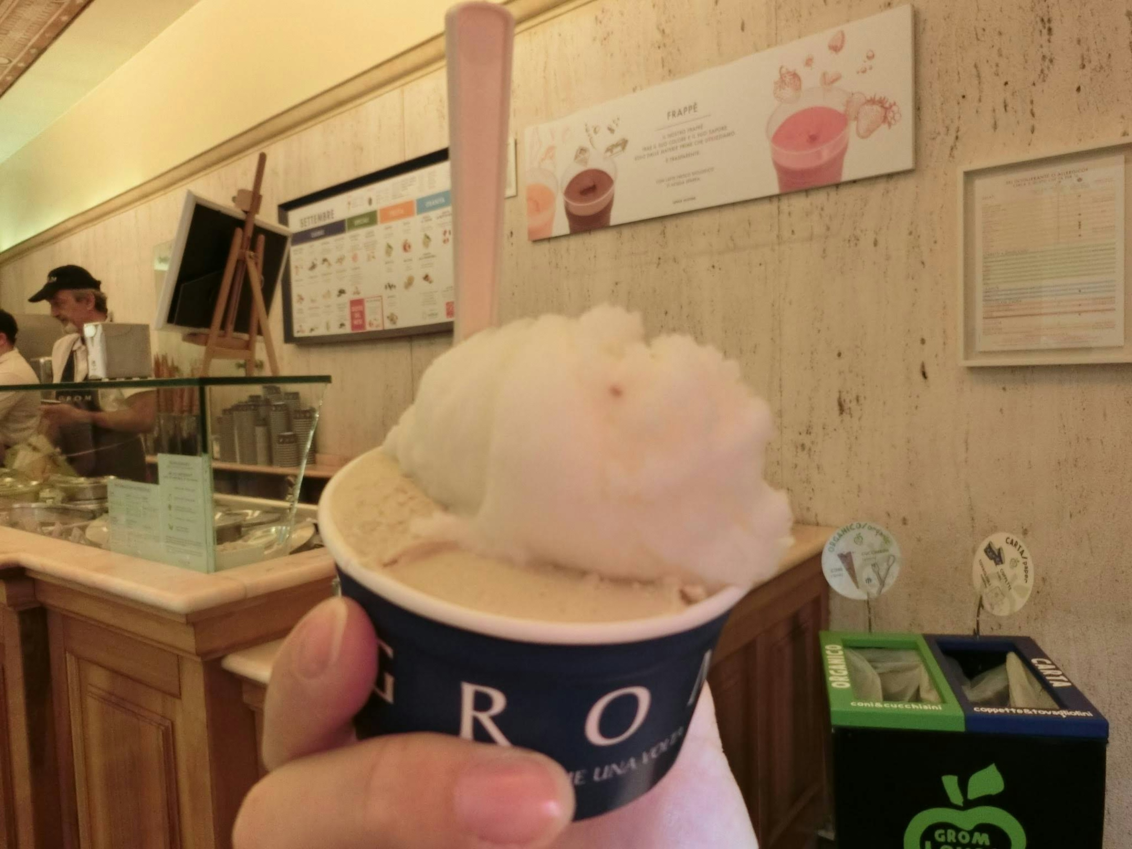 Hand holding a cup of gelato topped with fluffy cotton candy