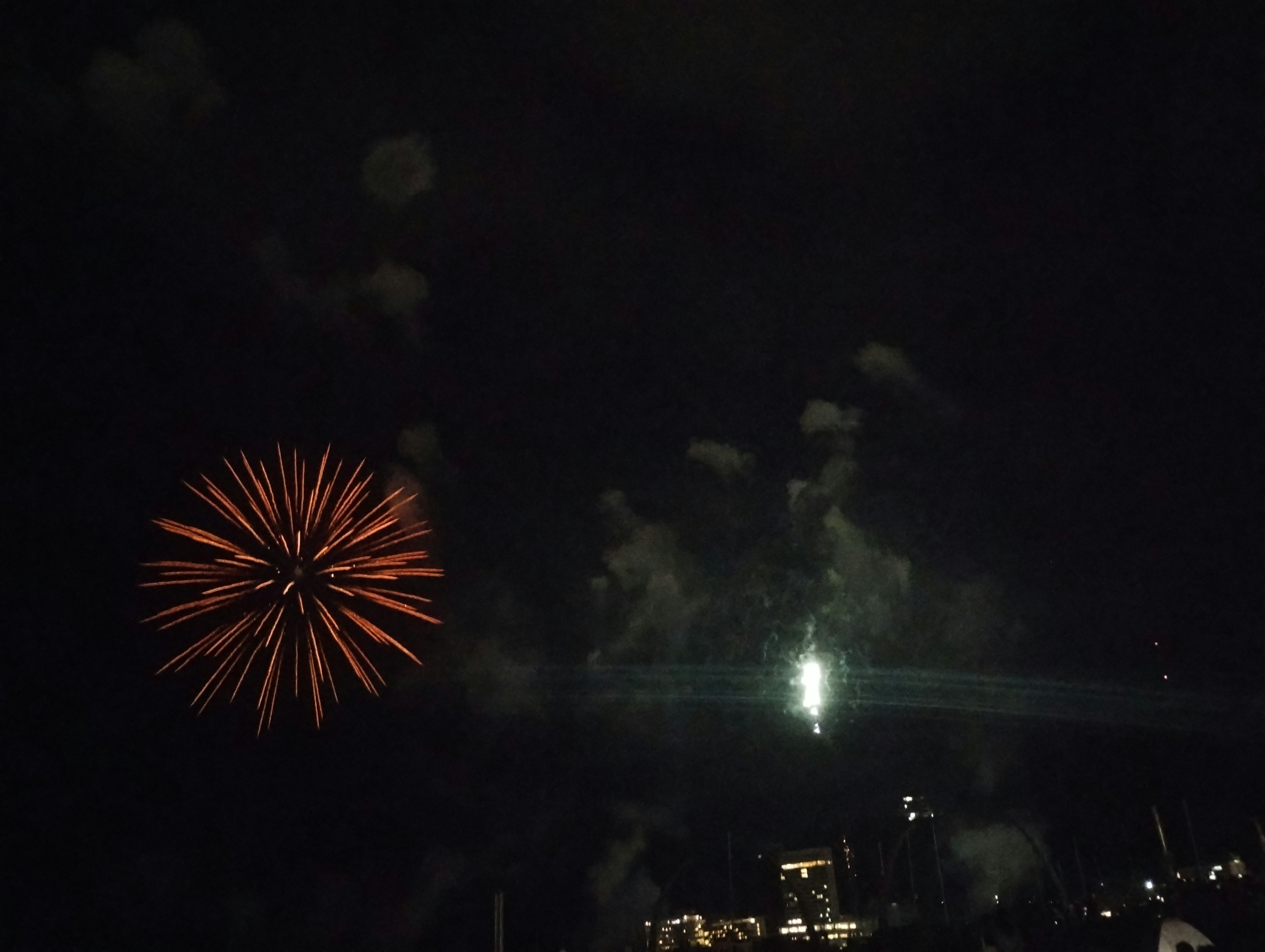 Orange Feuerwerk, das im Nachthimmel mit umliegendem Rauch explodiert